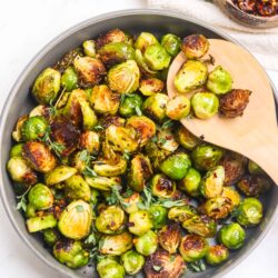 Roasted Brussels sprouts in a skillet with herbs and seasoning.