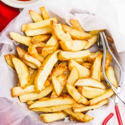 Crispy homemade French fries with golden edges served in a basket with ketchup on the side. Perfect comfort food and snack.