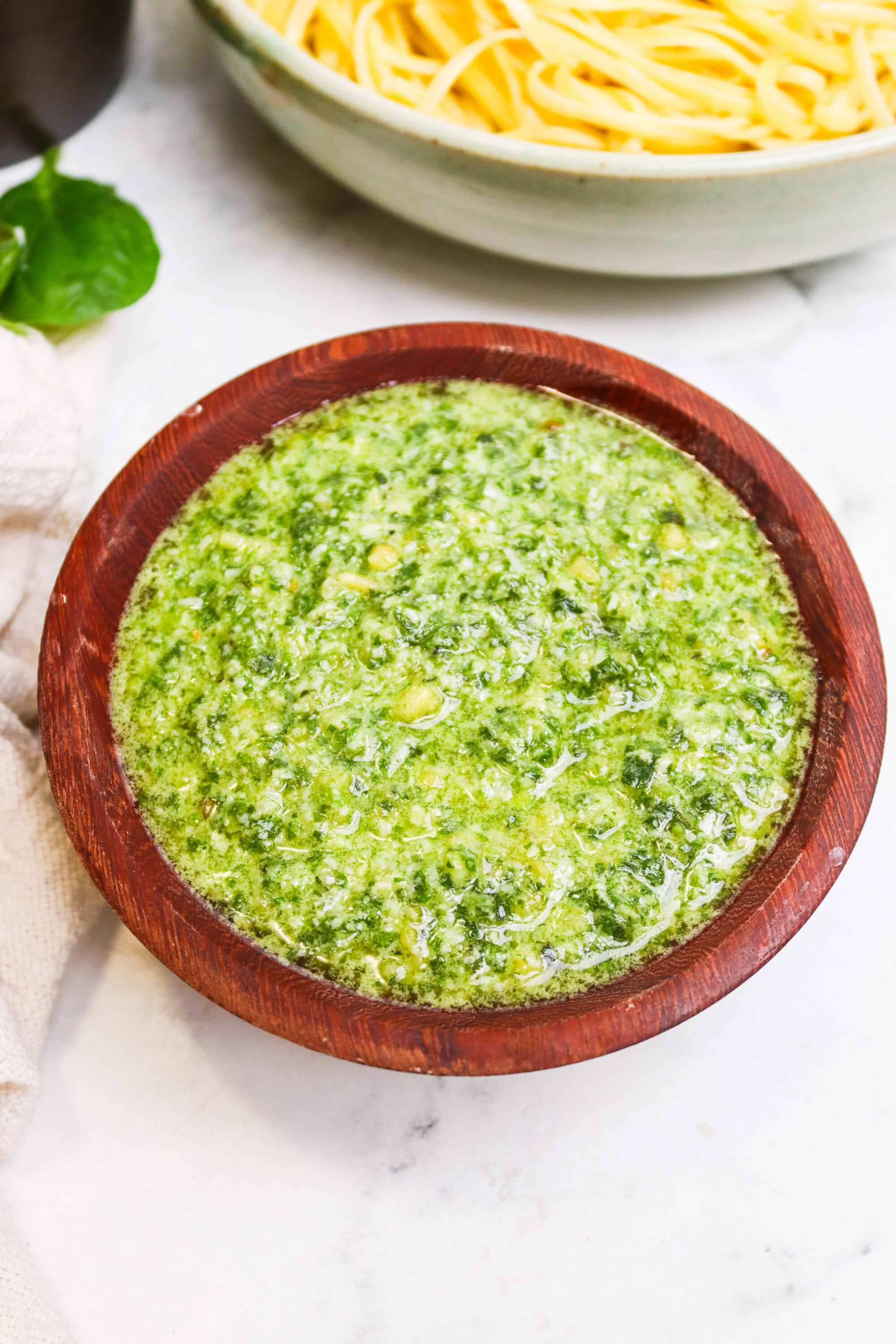 Creamy basil pesto sauce in a wooden bowl, perfect for pasta dishes.