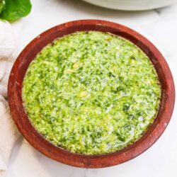 Creamy basil pesto sauce in a wooden bowl, perfect for pasta dishes.