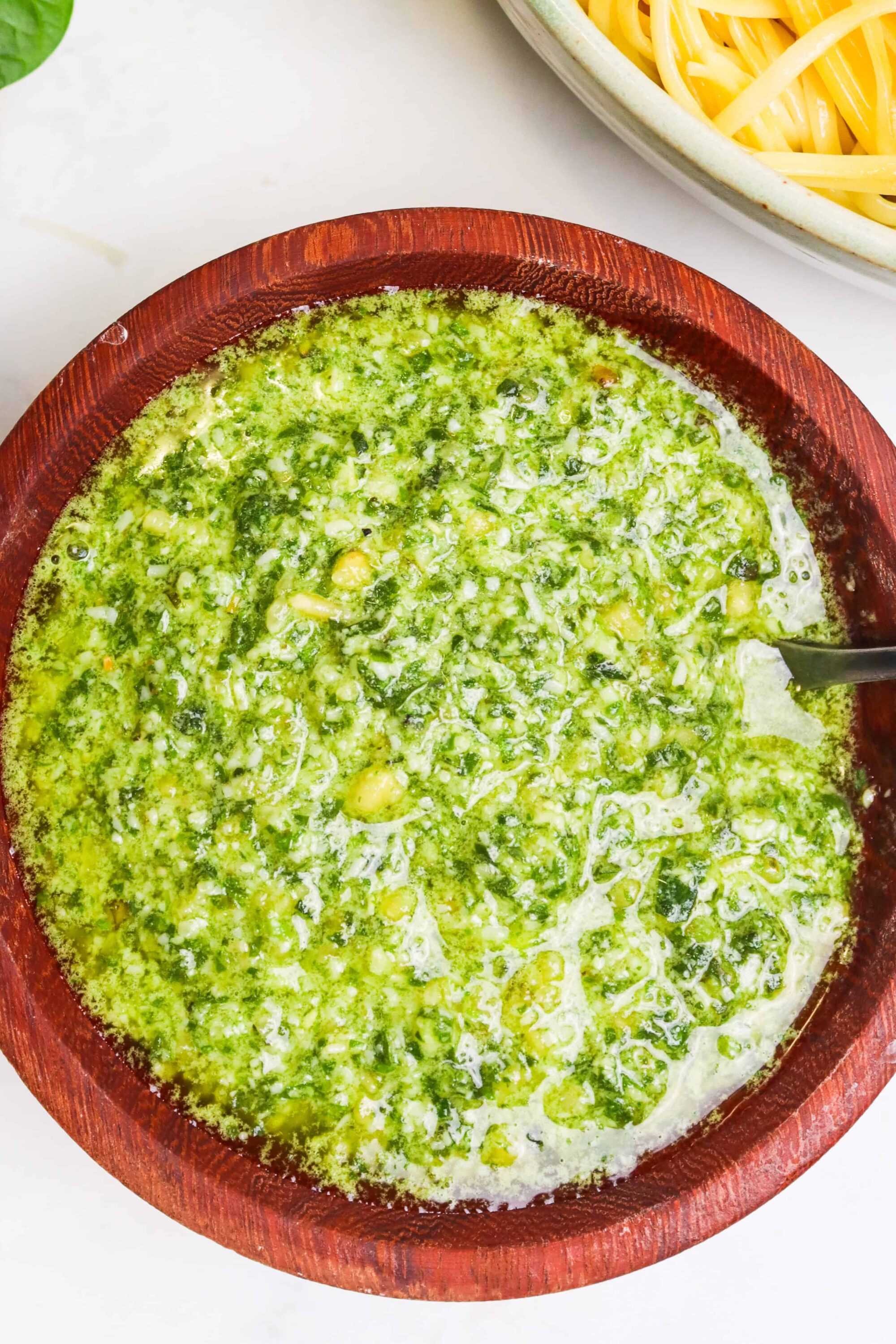 Creamy pesto soup with fresh herbs in a rustic wooden bowl.