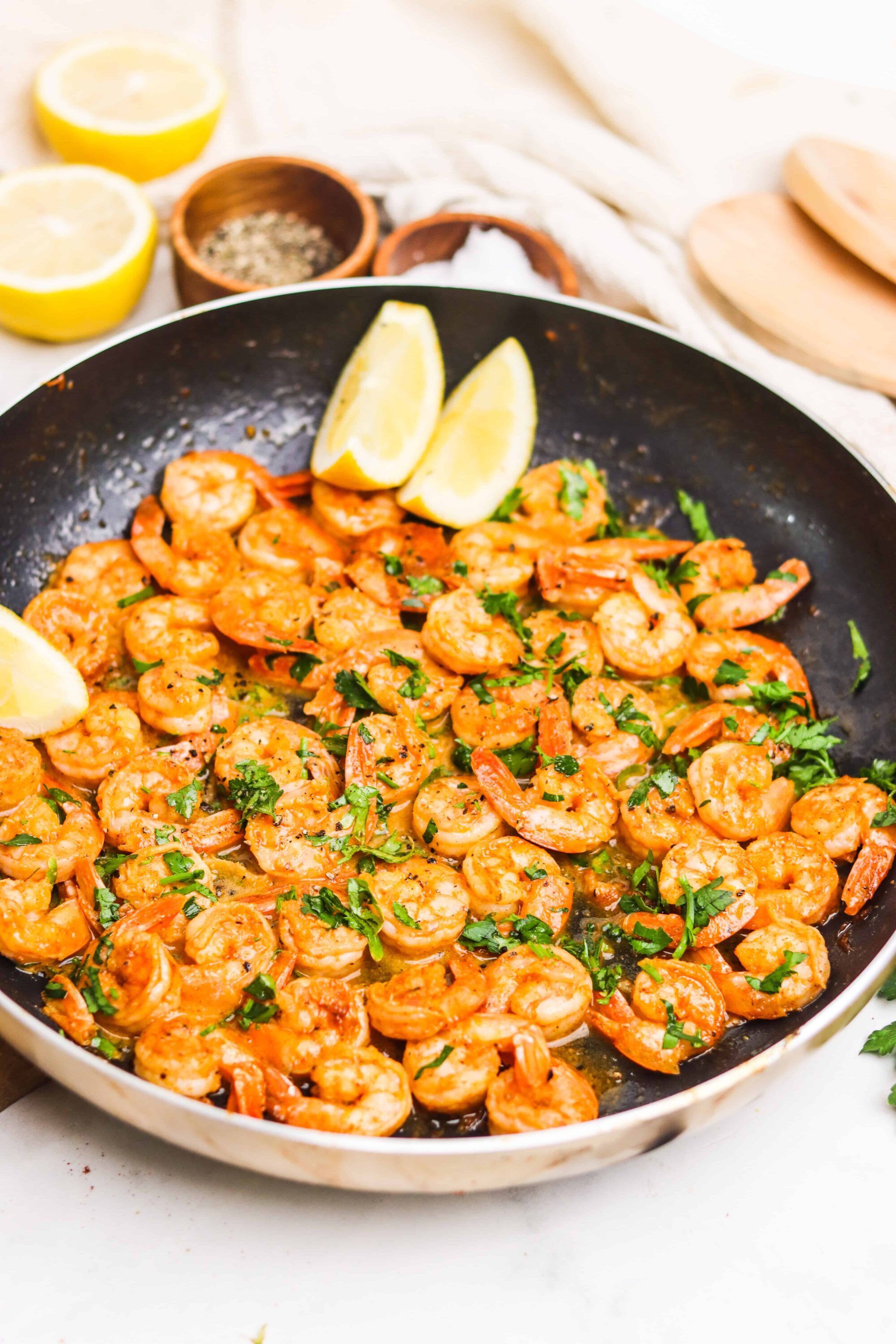 Sautéed shrimp with garlic, lemon, and fresh herbs in a black skillet.