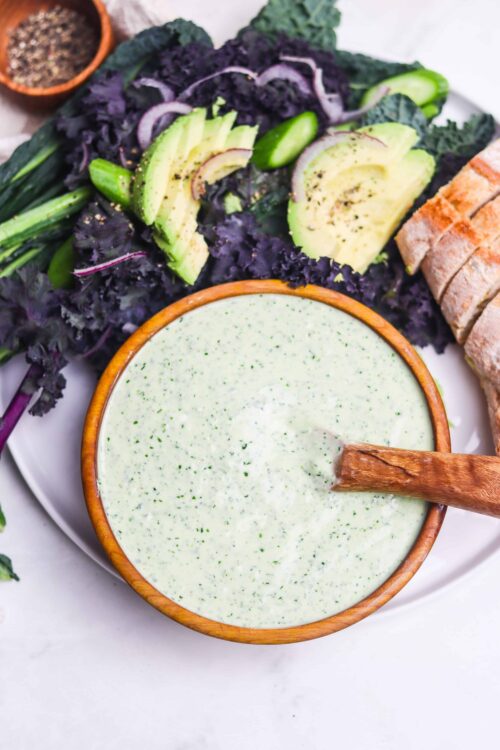 Creamy cucumber dill sauce with fresh vegetables and bread on a white plate, healthy homemade dressing.
