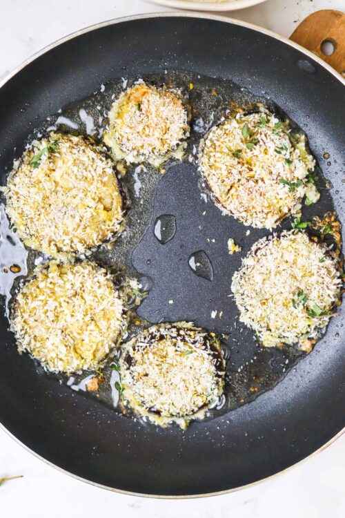 Cheese-stuffed mushroom caps baking in a skillet for a delicious appetizer or side dish.
