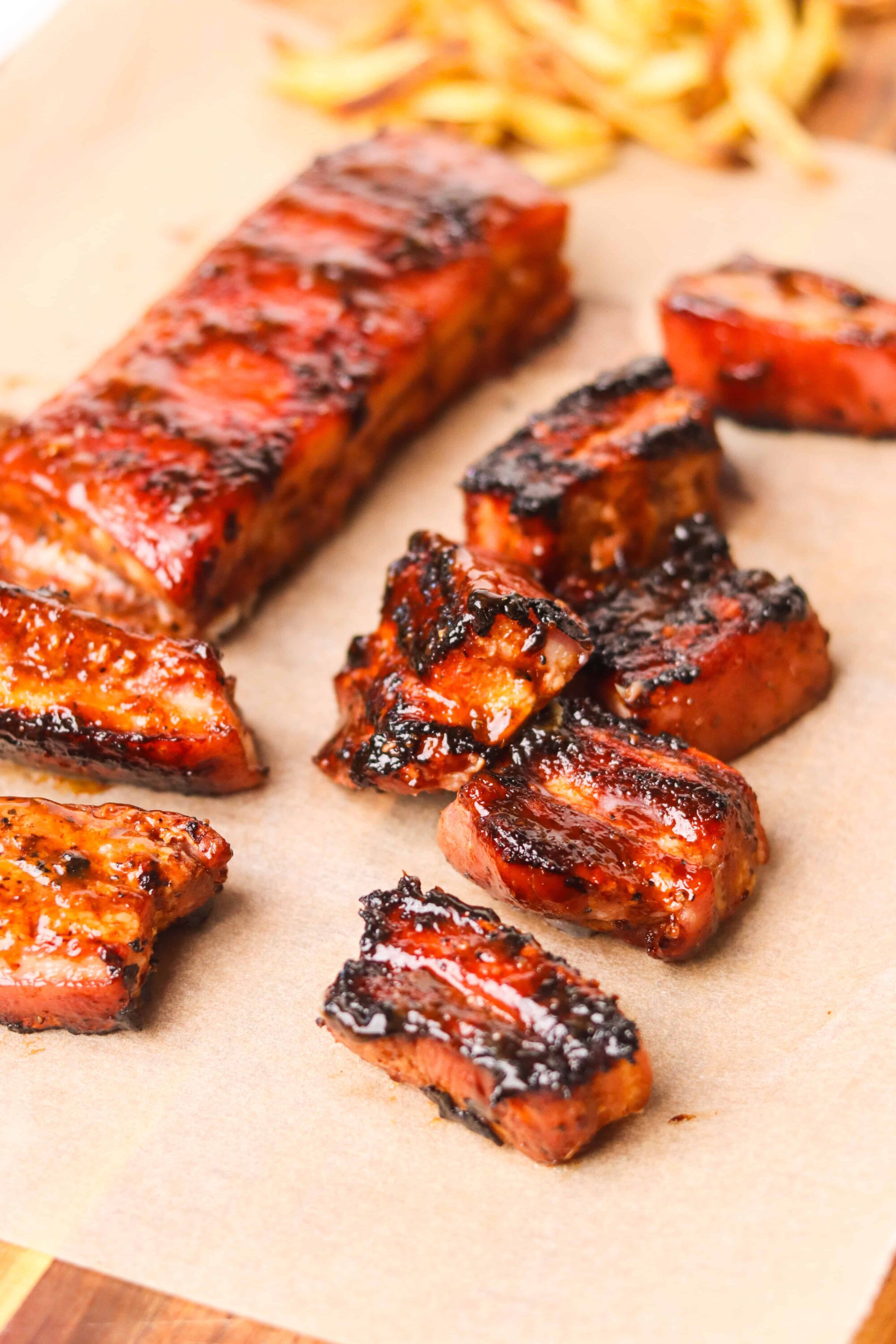 Smoked barbecue pork ribs on parchment paper with caramelized glaze.