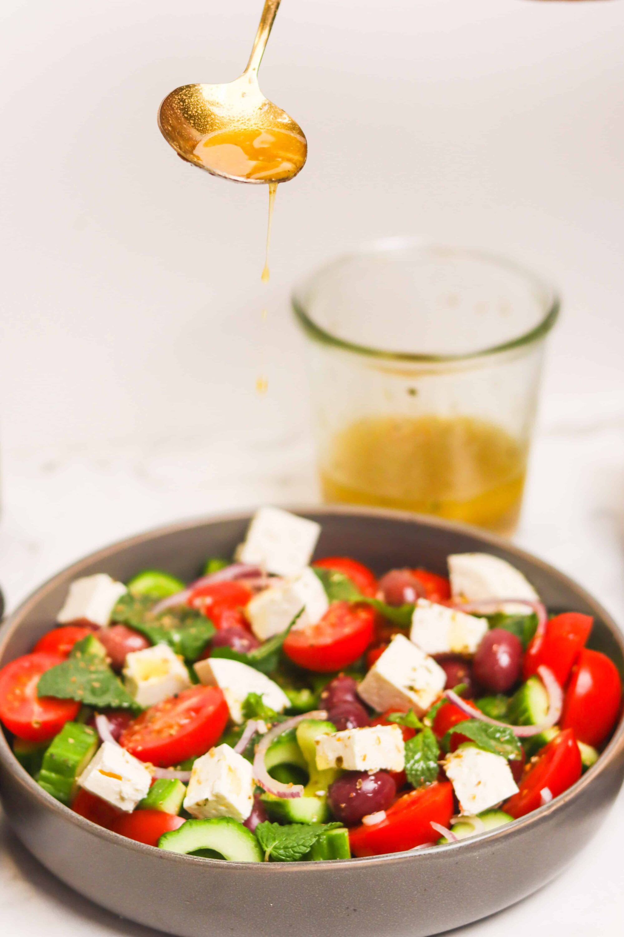 Fresh Greek salad with cherry tomatoes, cucumbers, feta cheese, red onions, and Kalamata olives, drizzled with olive oil.