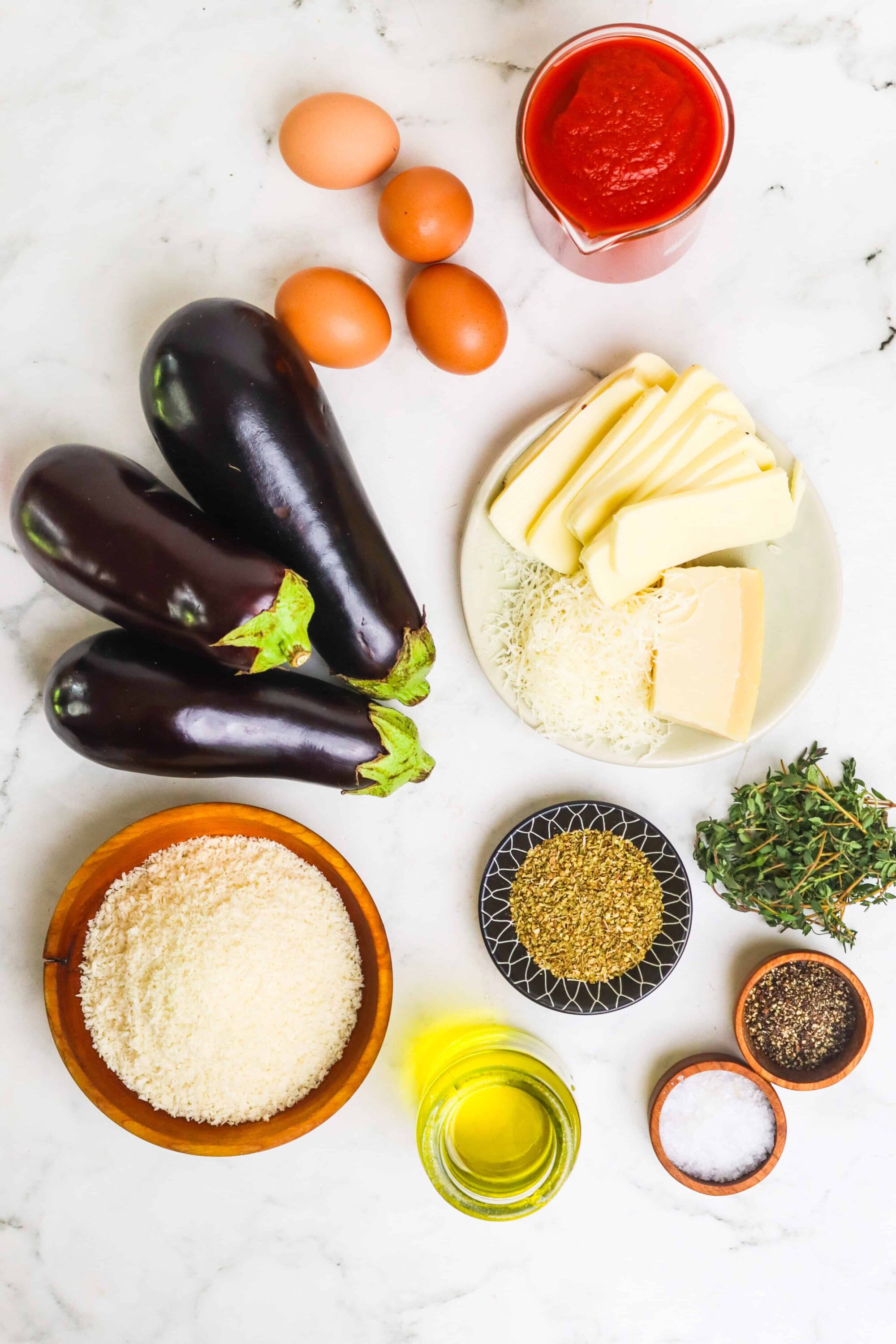 Fresh eggplant, cheese, tomato sauce, breadcrumbs, herbs, and seasonings for eggplant parmesan.