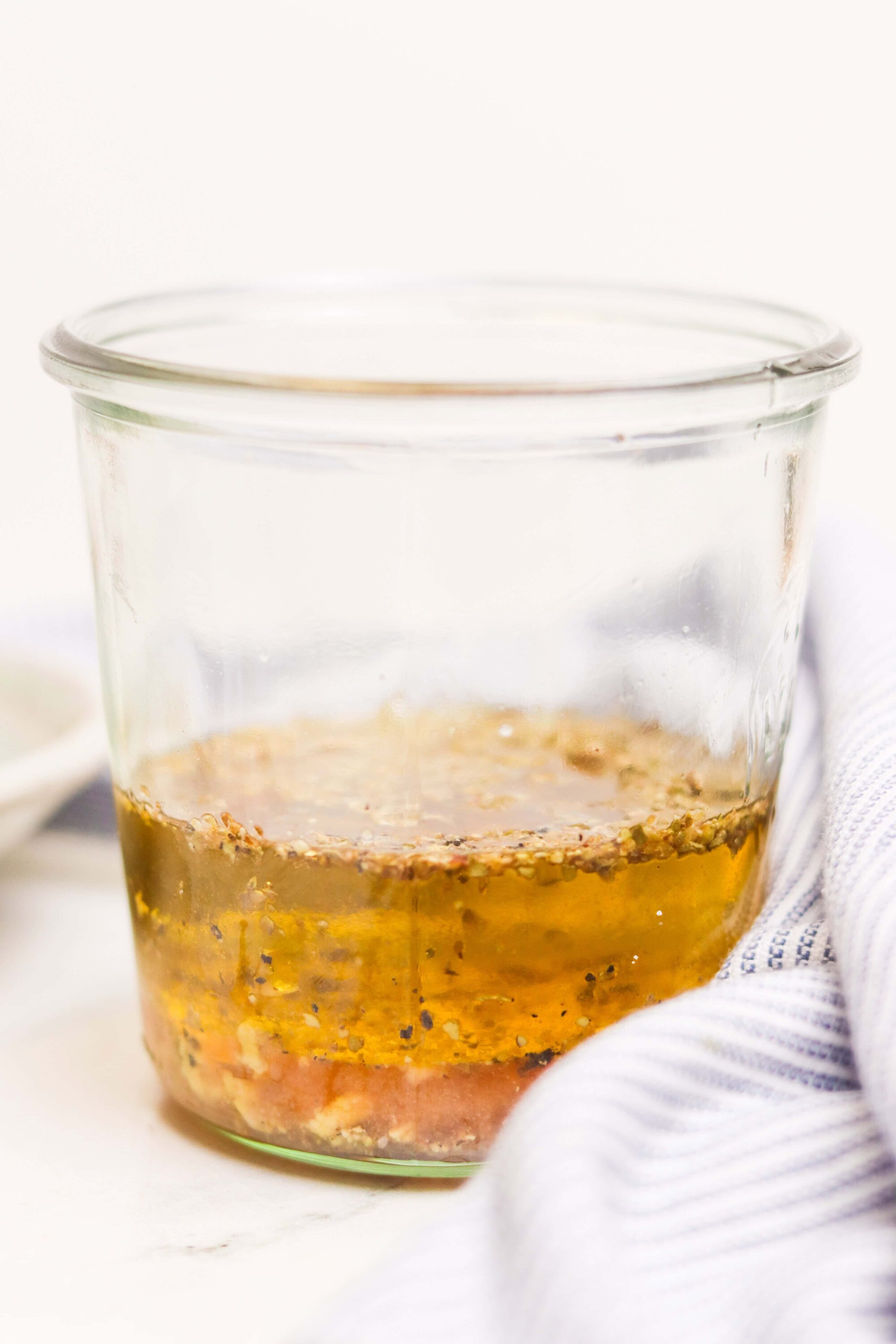 Liquid marinade with spices and herbs in a glass jar for baking or cooking.