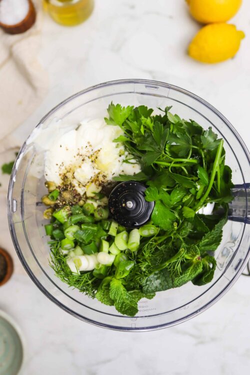 Fresh herbs, green onions, garlic, and mayonnaise in a food processor for herb sauce.