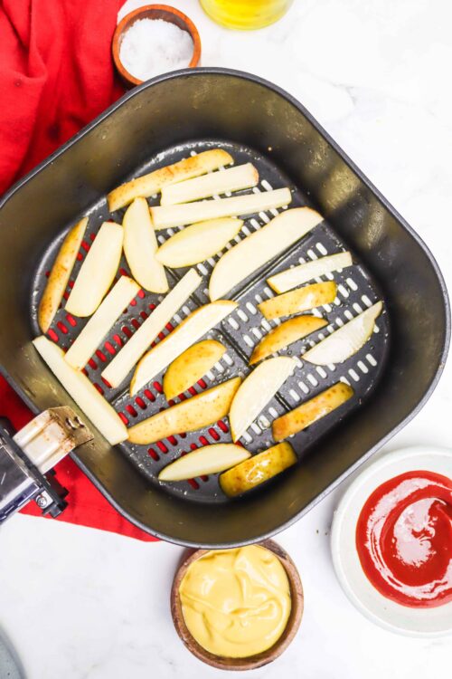 Crispy air fryer potato wedges on a black baking tray. Perfect for homemade snacks and easy appetizers.
