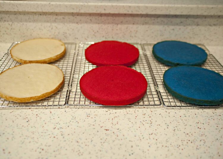 Foam cookie cutters in red, blue, and white on cooling racks with a speckled countertop background|red, blue, and white foam cookie cutters cooling on racks|Colorful foam cookie cutters in red, blue, and white cooling on wire racks, ready for baking or crafting projects|A set of foam cookie cutters in red, blue, and white arranged on wire cooling racks on a speckled countertop, suitable for baking or kids' crafts|relevance.