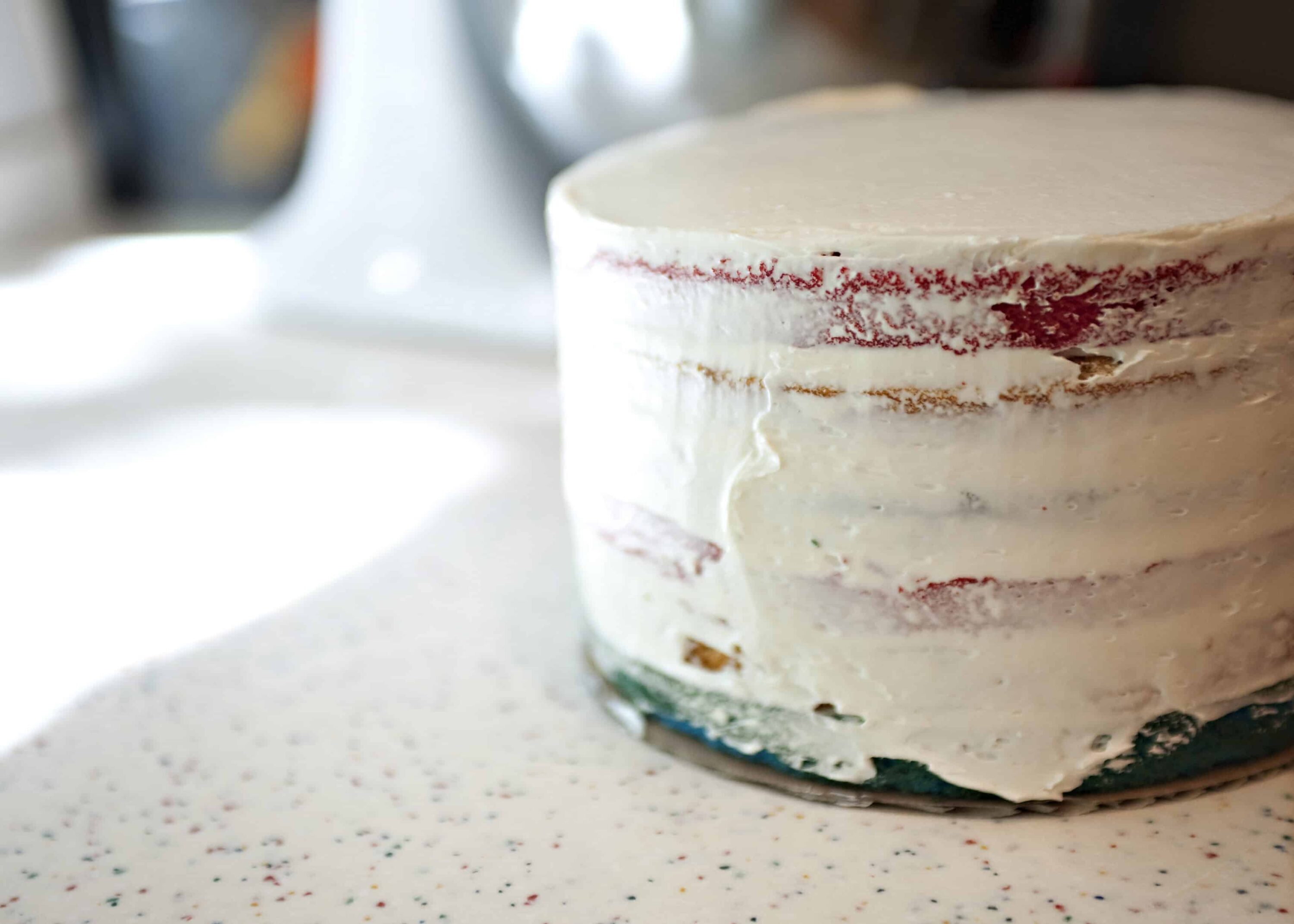 Buttercream frosted naked cake with red velvet layers and rustic finish.