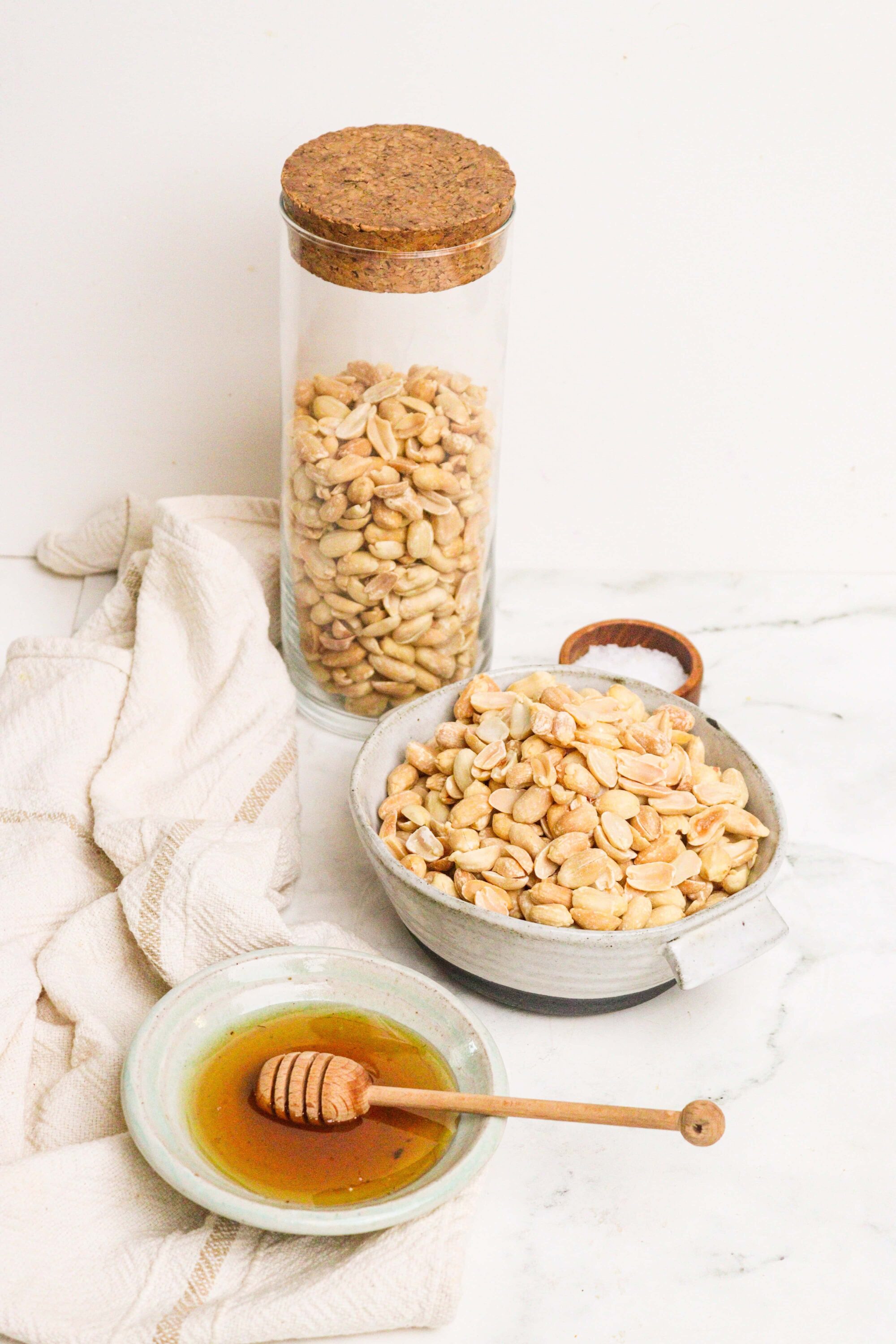 Roasted peanuts with honey, salt, and baking ingredients for homemade peanut butter.