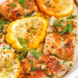 Juicy baked chicken with lemon and herbs in a white dish, perfect for healthy dinner recipes.