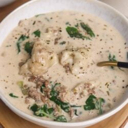 Creamy homemade chicken and shrimp chowder in a white bowl with greens, perfect for cozy comfort food.