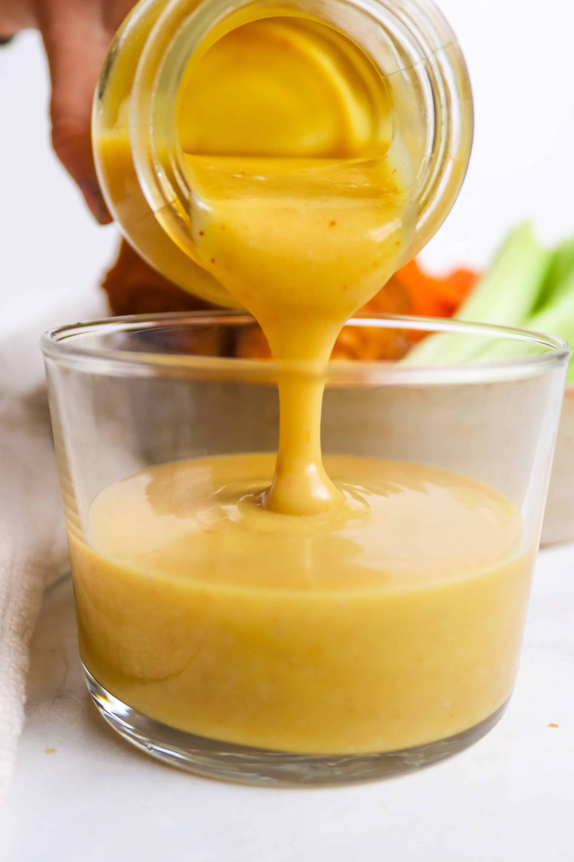 Rich, creamy honey mustard dipping sauce being poured into a glass.