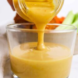 Rich, creamy honey mustard dipping sauce being poured into a glass.
