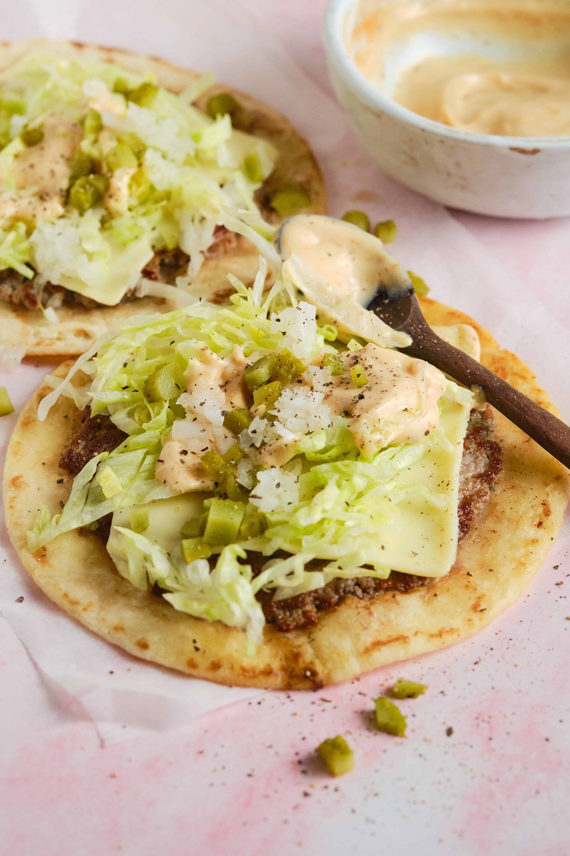 Fresh ground beef and cheese tacos topped with shredded lettuce, chopped onions, and chopped pickles on soft tortillas.