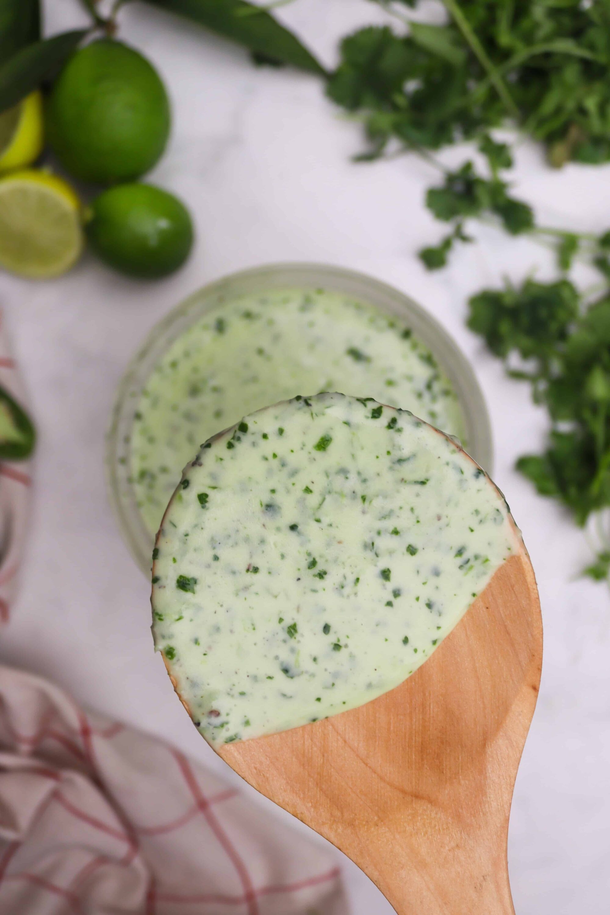 Creamy cilantro lime dressing on wooden spoon for salads and tacos.