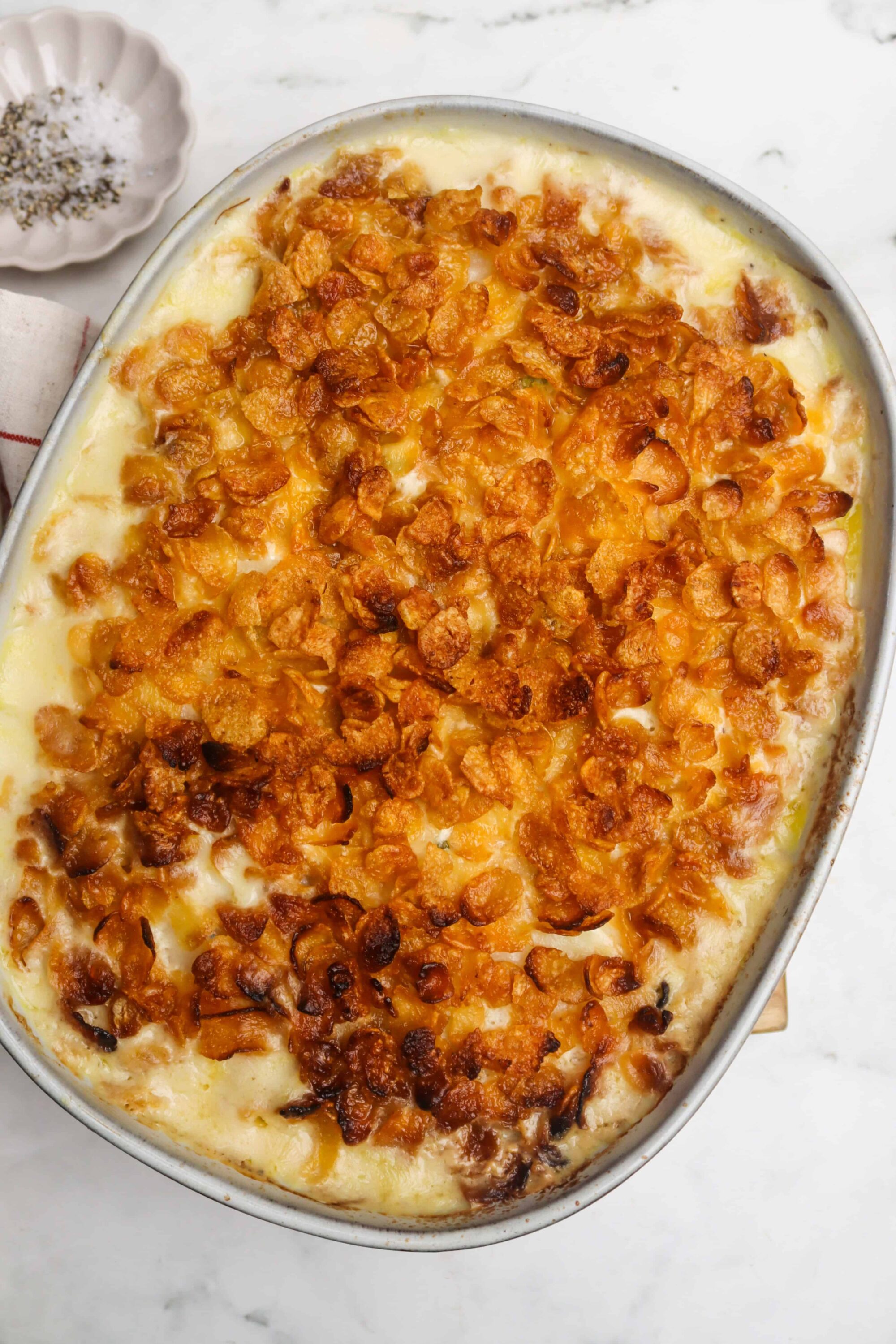 Golden baked macaroni and cheese with crispy breadcrumb topping, served in a white baking dish.