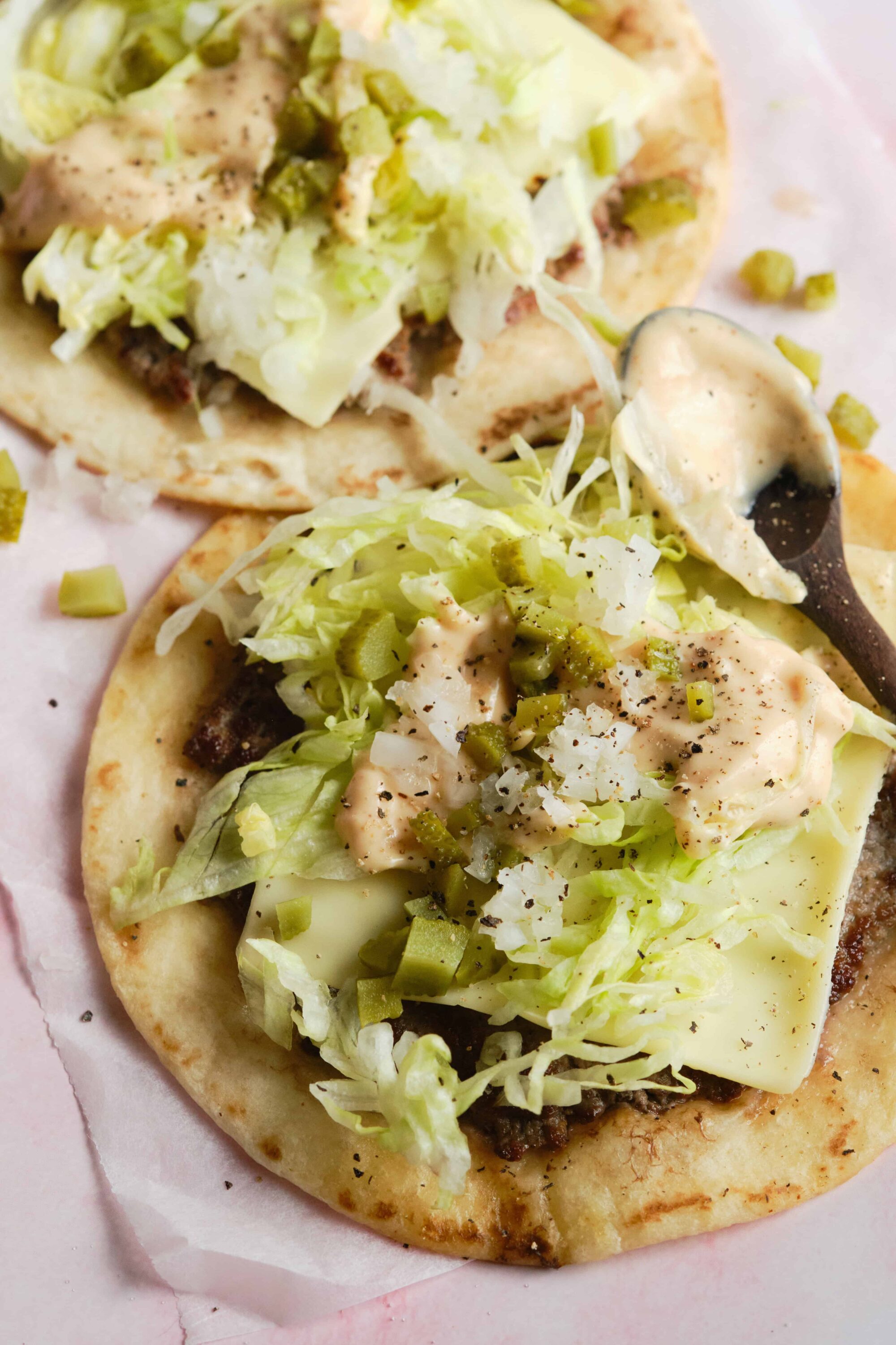 Crispy fish tacos with lettuce, cheese, and creamy sauce on flatbread, close-up, Baked Bree style.