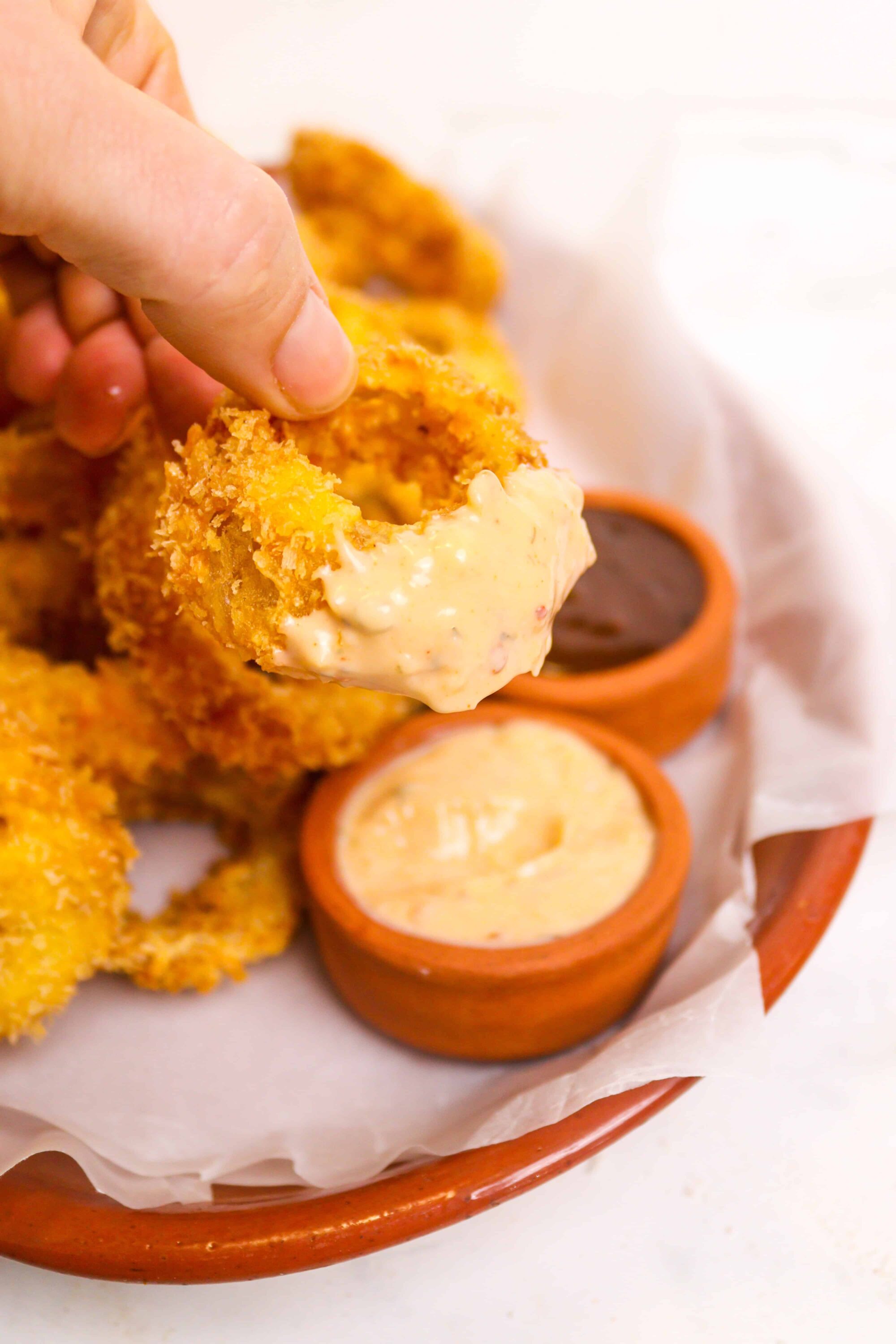 Crispy fried chicken tenders with creamy dipping sauces in a basket, perfect for comfort food lovers.