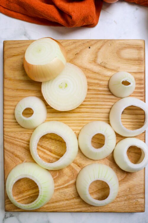 Sliced yellow onions on a wooden cutting board for cooking or recipes.