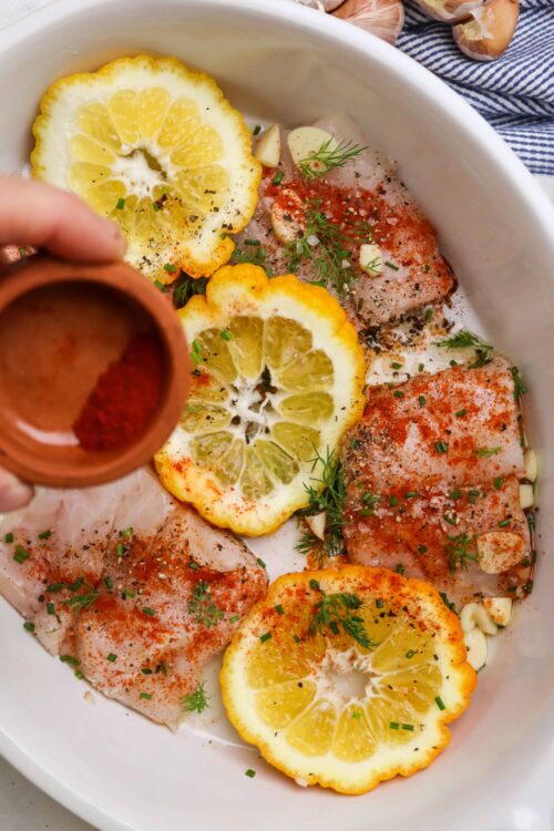 Lemon chicken with garlic, herbs, and seasonings in a baking dish for delicious baked chicken recipes.