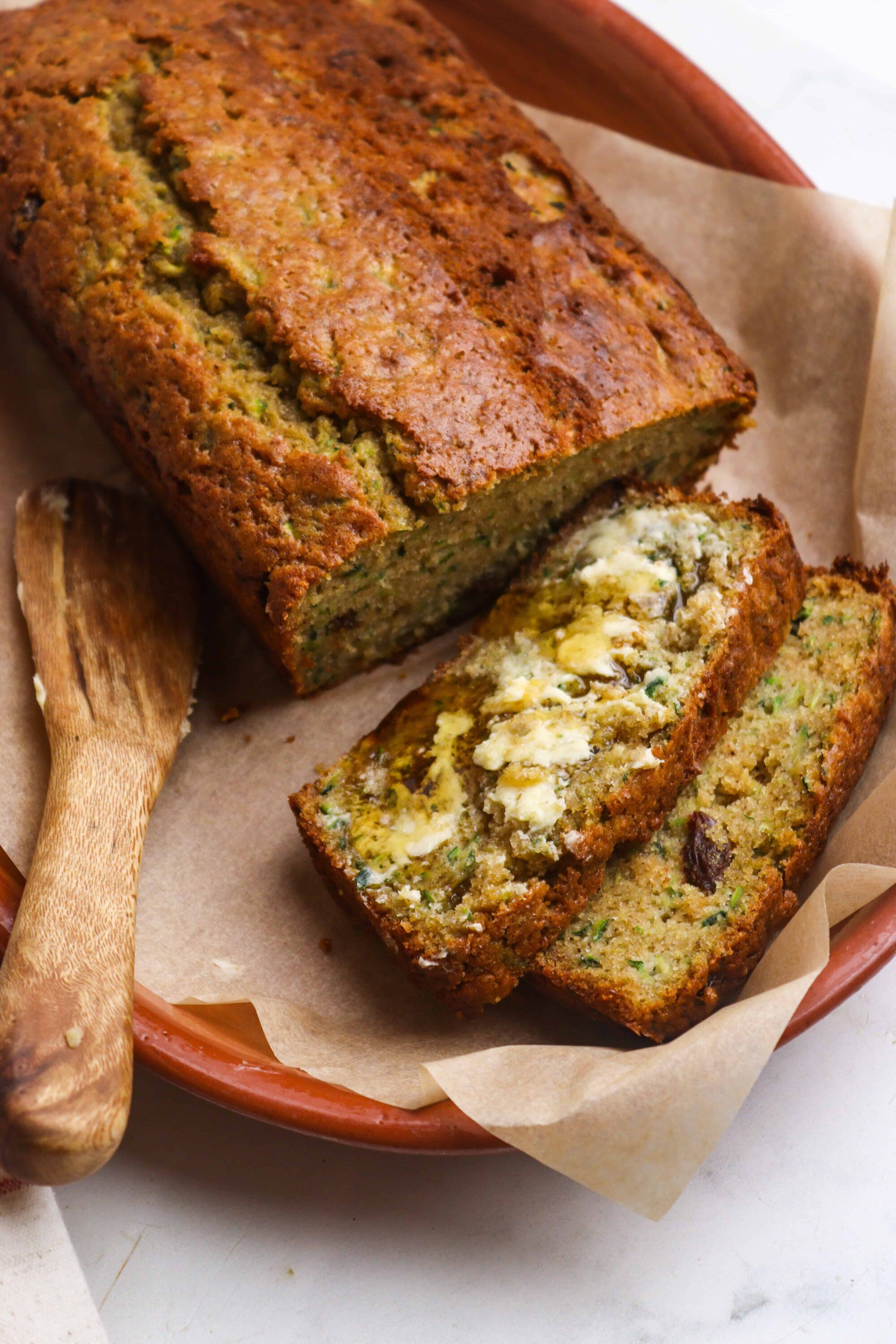 Moist zucchini bread with walnuts and raisins baked to perfection in a terracotta dish.