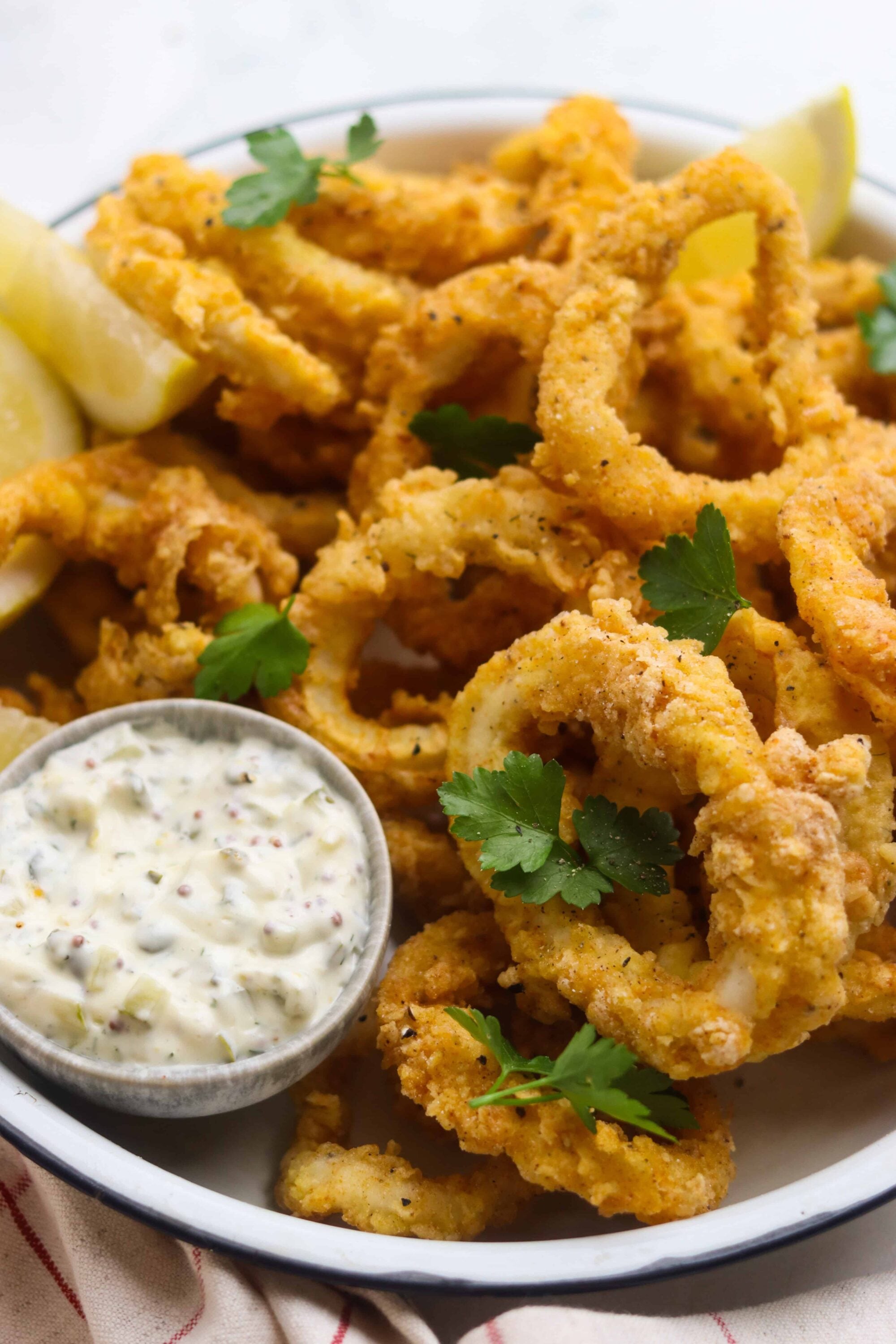 Crispy fried calamari with lemon wedges and tartar sauce, served as a seafood appetizer.
