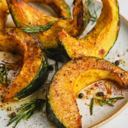 Roasted acorn squash slices with herbs and spices, perfect for fall or holiday dinners. Delicious and healthy vegetable side dish.