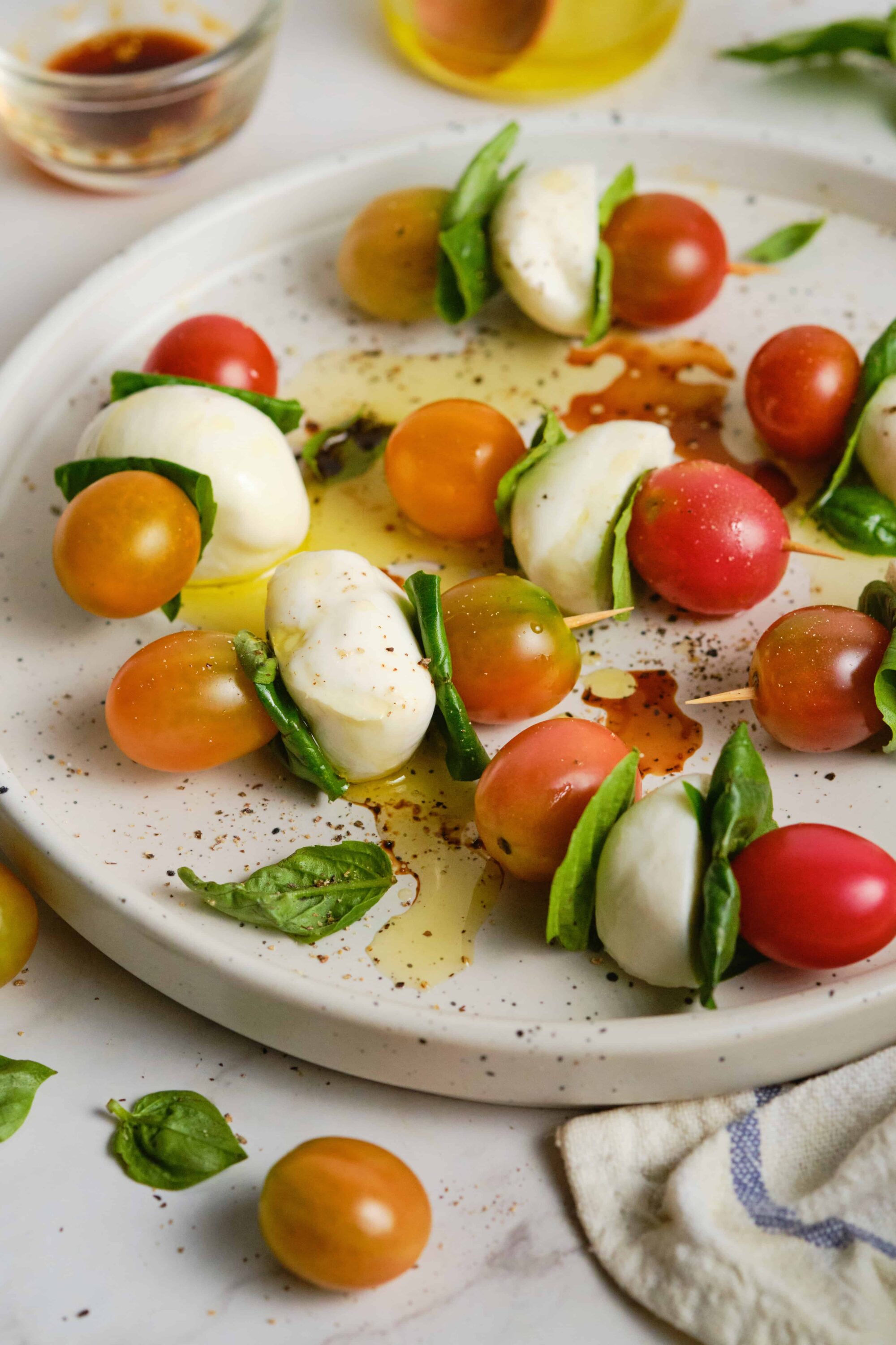 Fresh mozzarella, cherry tomatoes, basil, olive oil, and balsamic vinegar on a white plate.