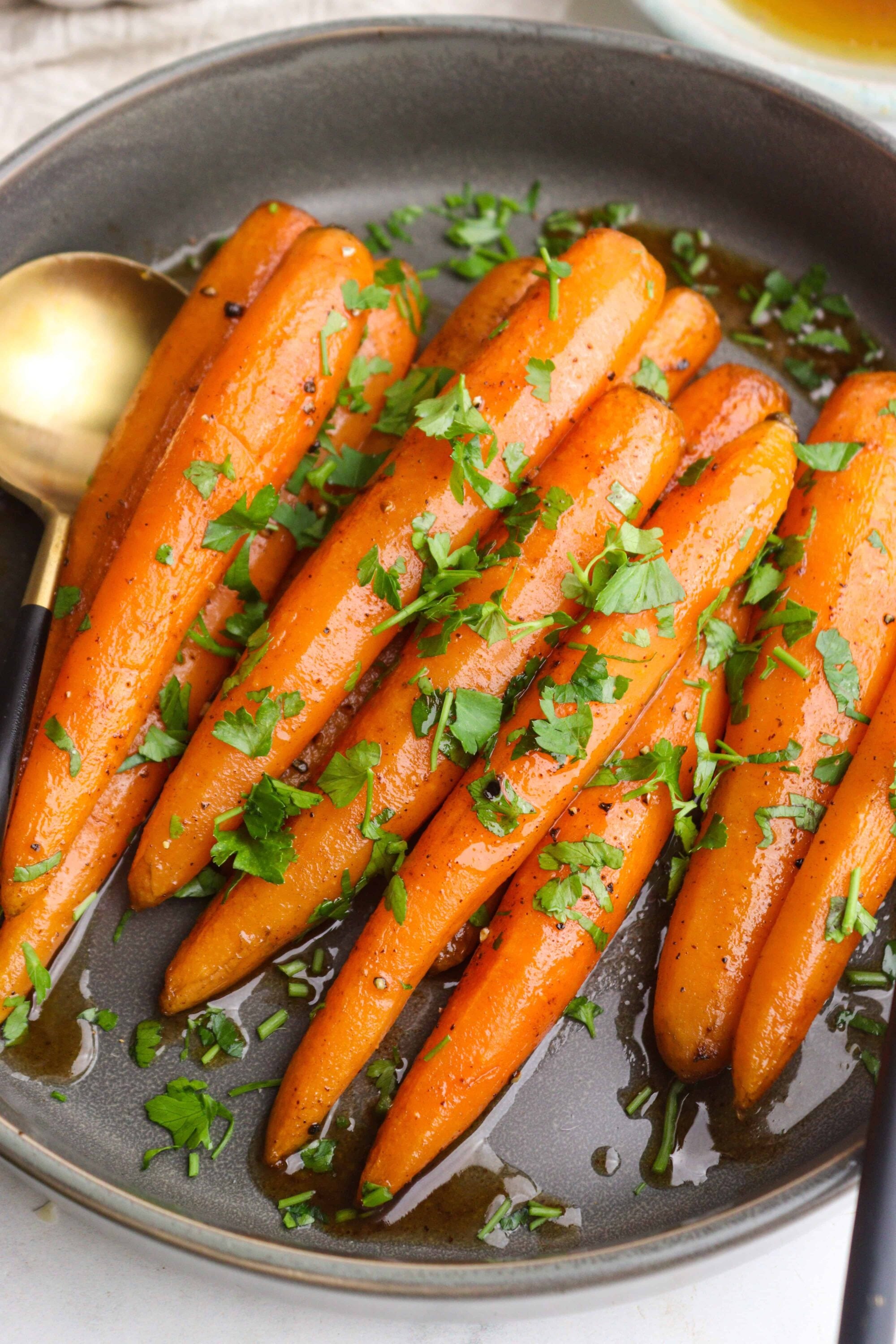 Roasted carrots with fresh parsley and garlic butter in a skillet, healthy vegetable side dish, vibrant orange color.