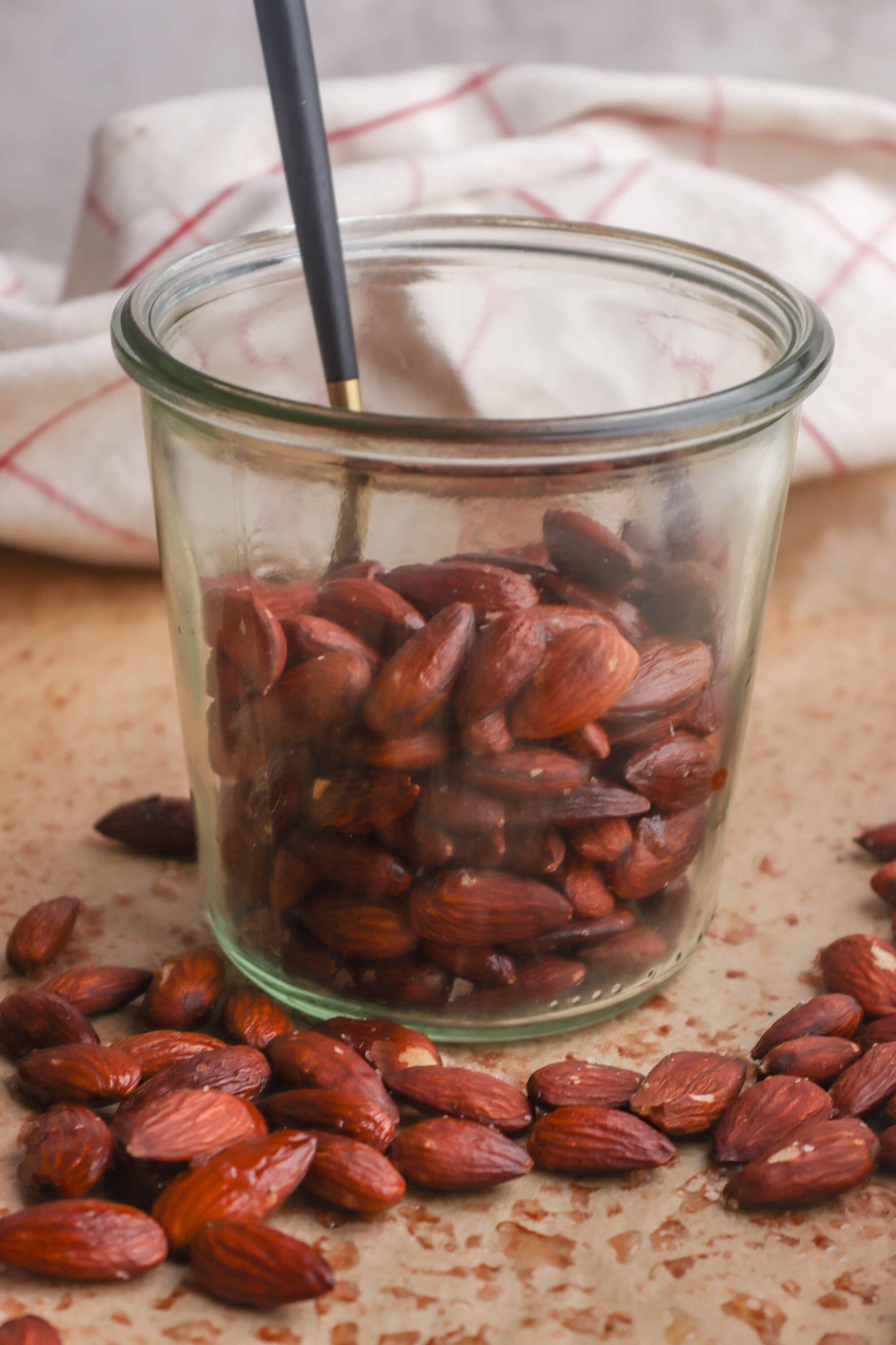 Roasted almonds in glass jar on kitchen countertop.