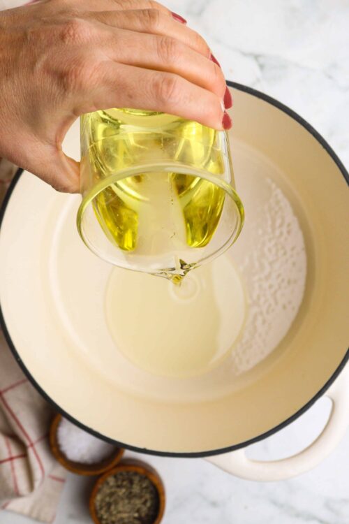 Golden olive oil being poured into a mixing bowl for baking or cooking preparation.