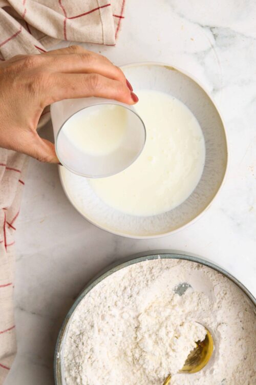 Cream being poured into flour mixture for baking recipes.