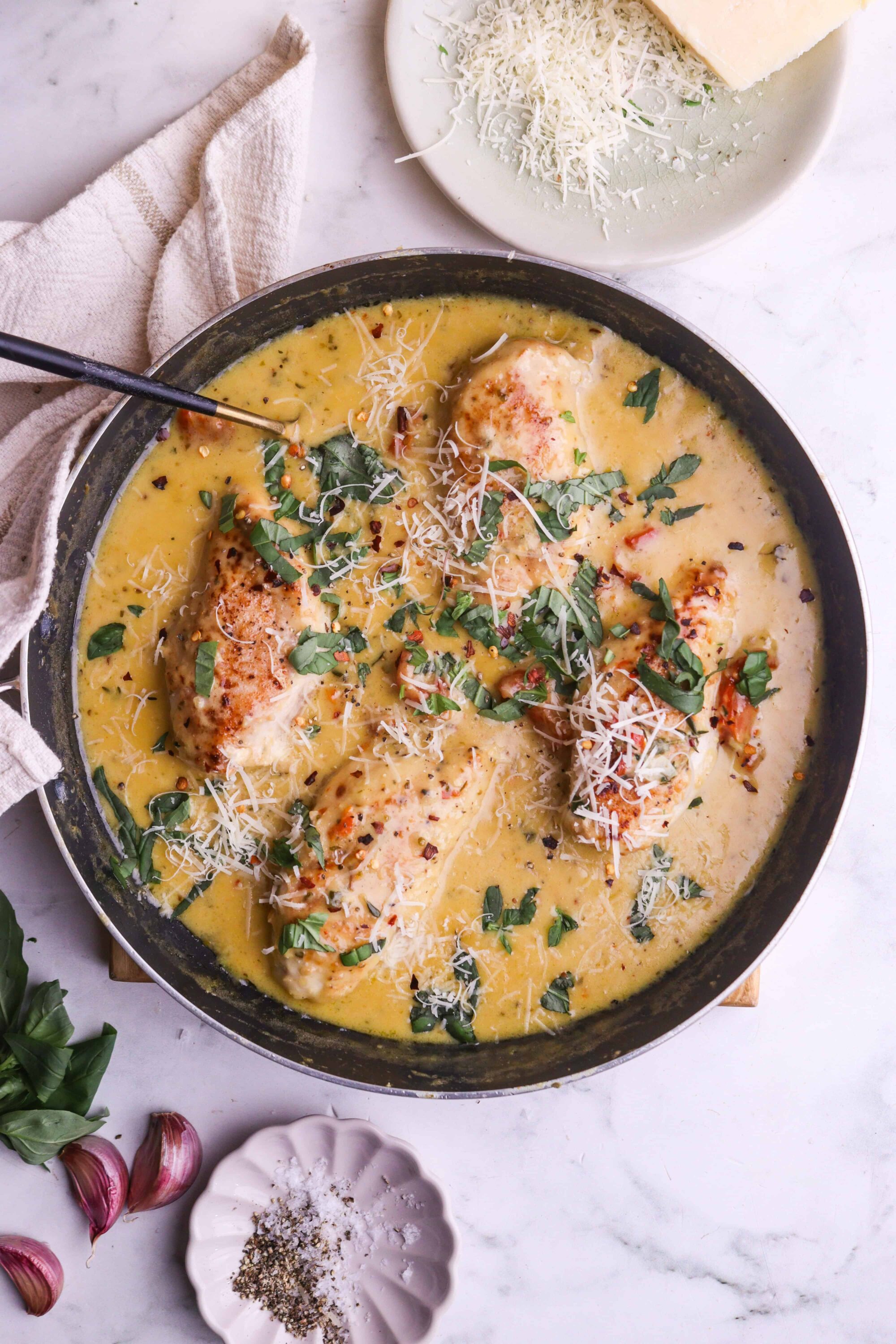 Creamy chicken and cheese casserole in a skillet garnished with fresh herbs and grated cheese. Perfect comfort food recipe from Baked Bree.