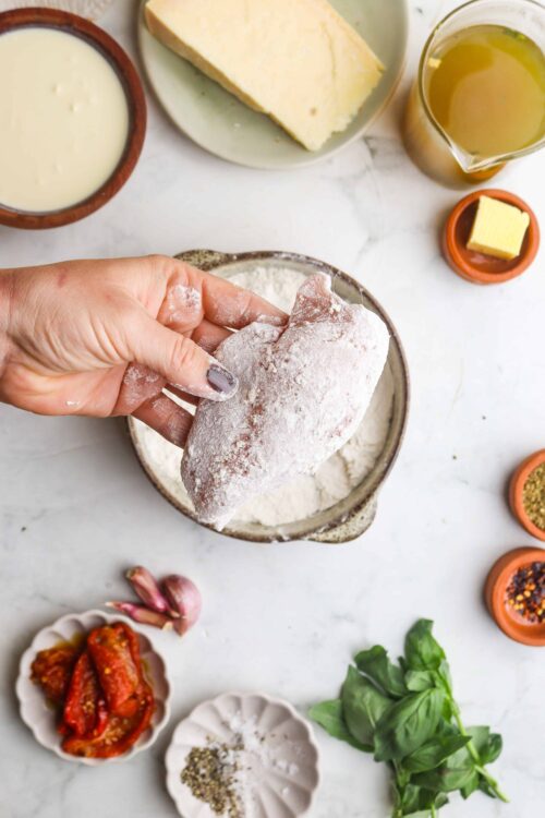 Cracked chicken being breaded with flour for cooking.