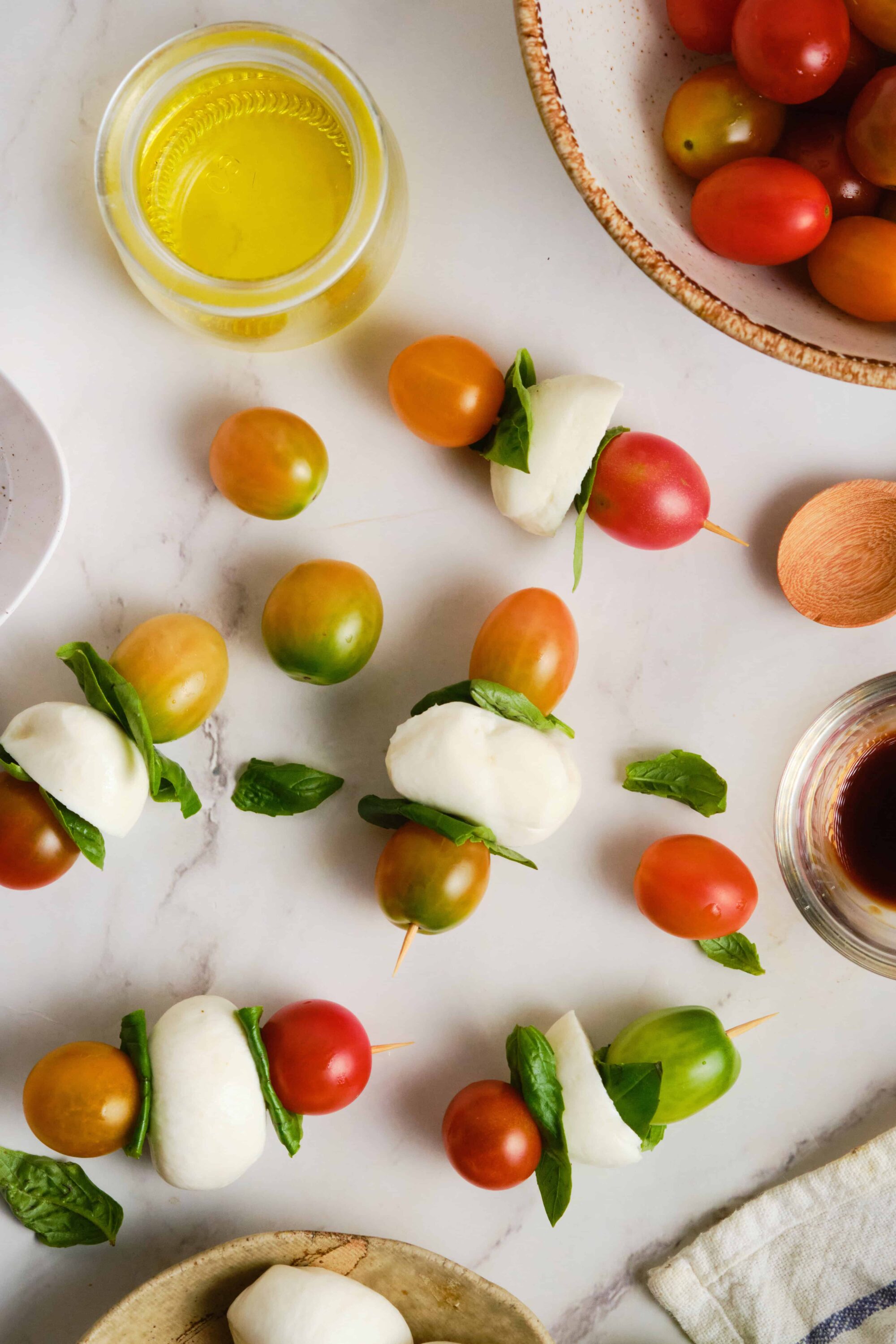 Fresh mozzarella, cherry tomatoes, basil, olive oil, and balsamic vinegar on a white marble surface.