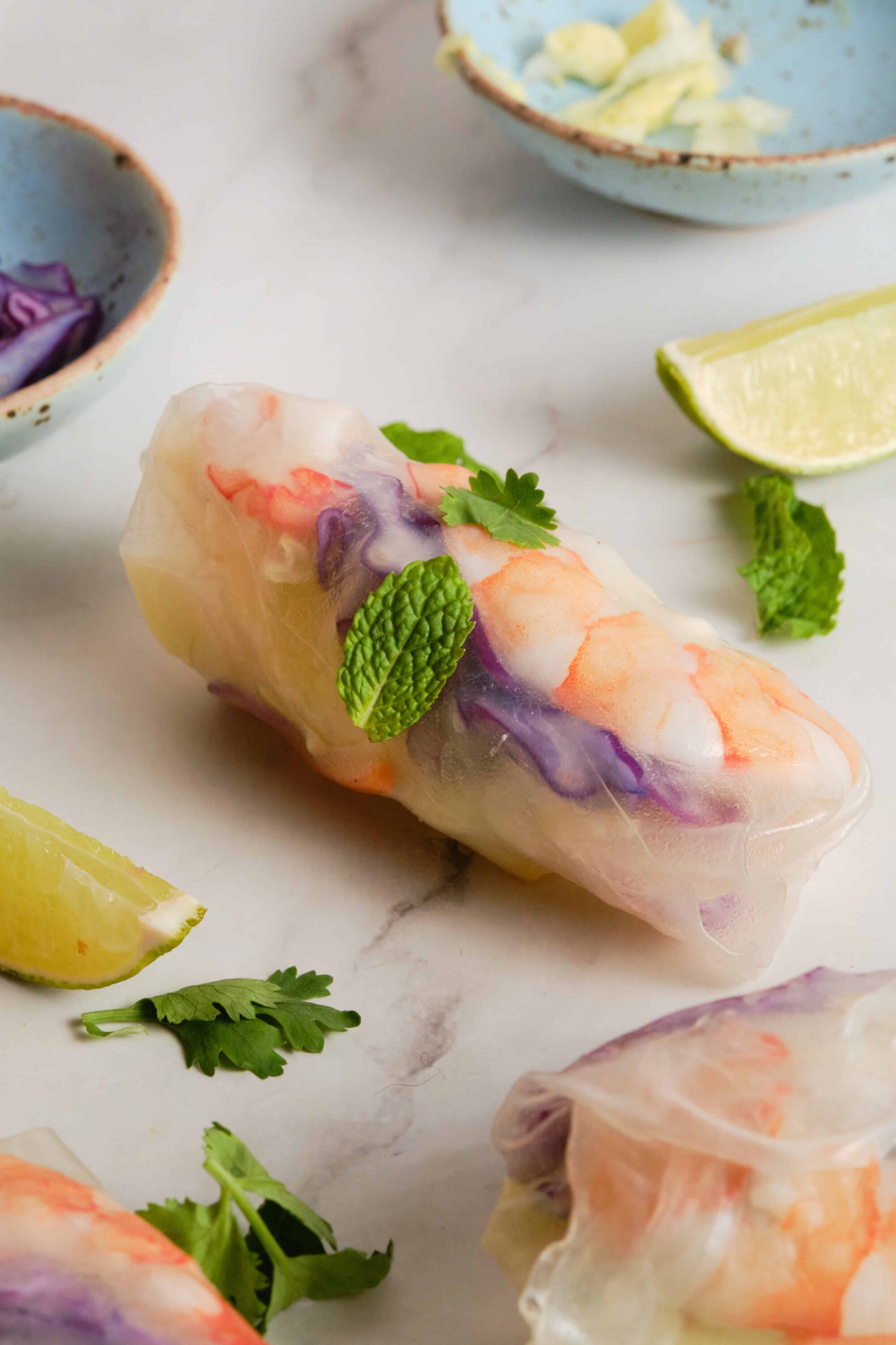 Fresh Vietnamese spring roll with shrimp, vegetables, and herbs on a white marble surface.