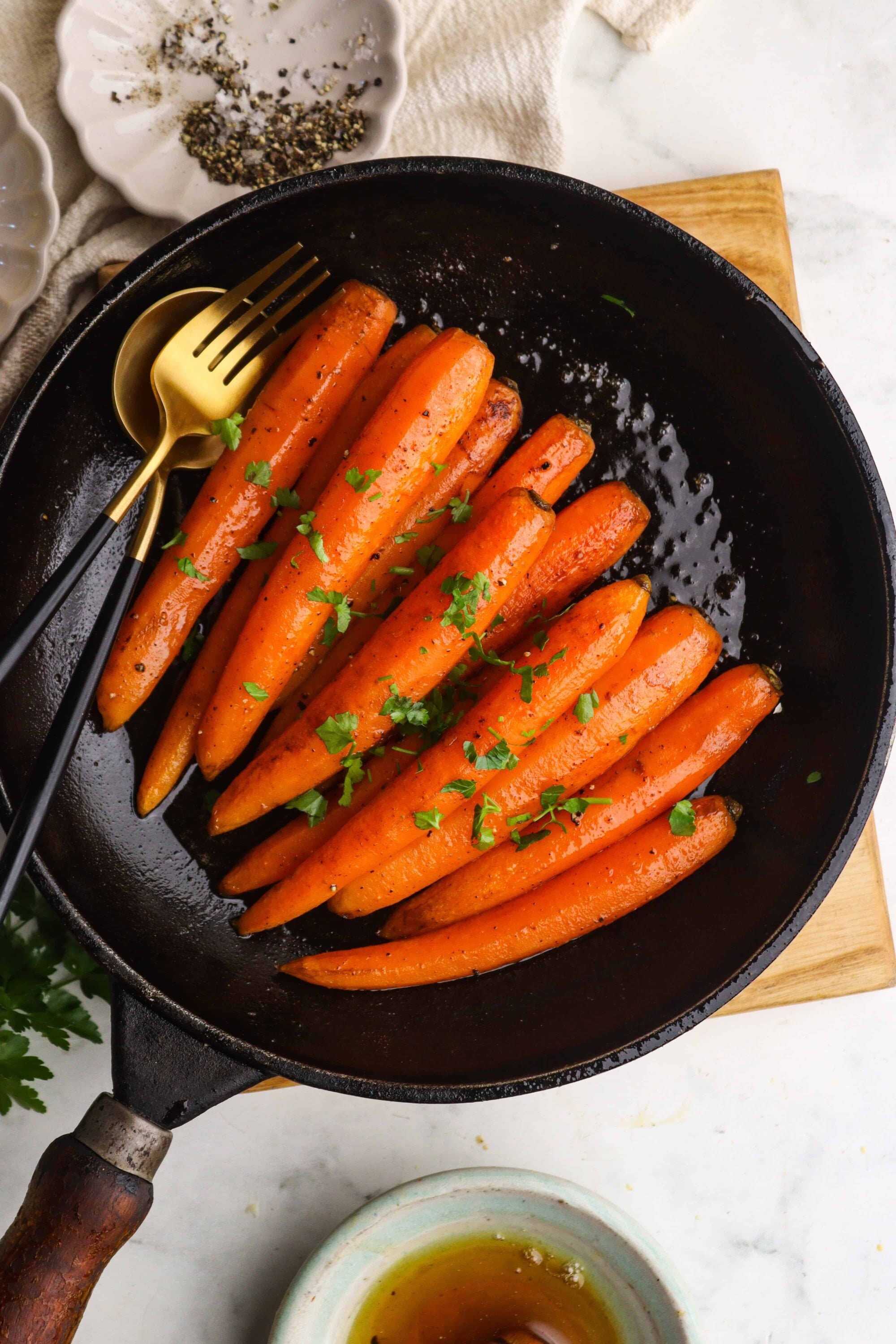 Roasted carrots with fresh herbs in a black skillet, healthy vegetable side dish, vegetarian recipe.