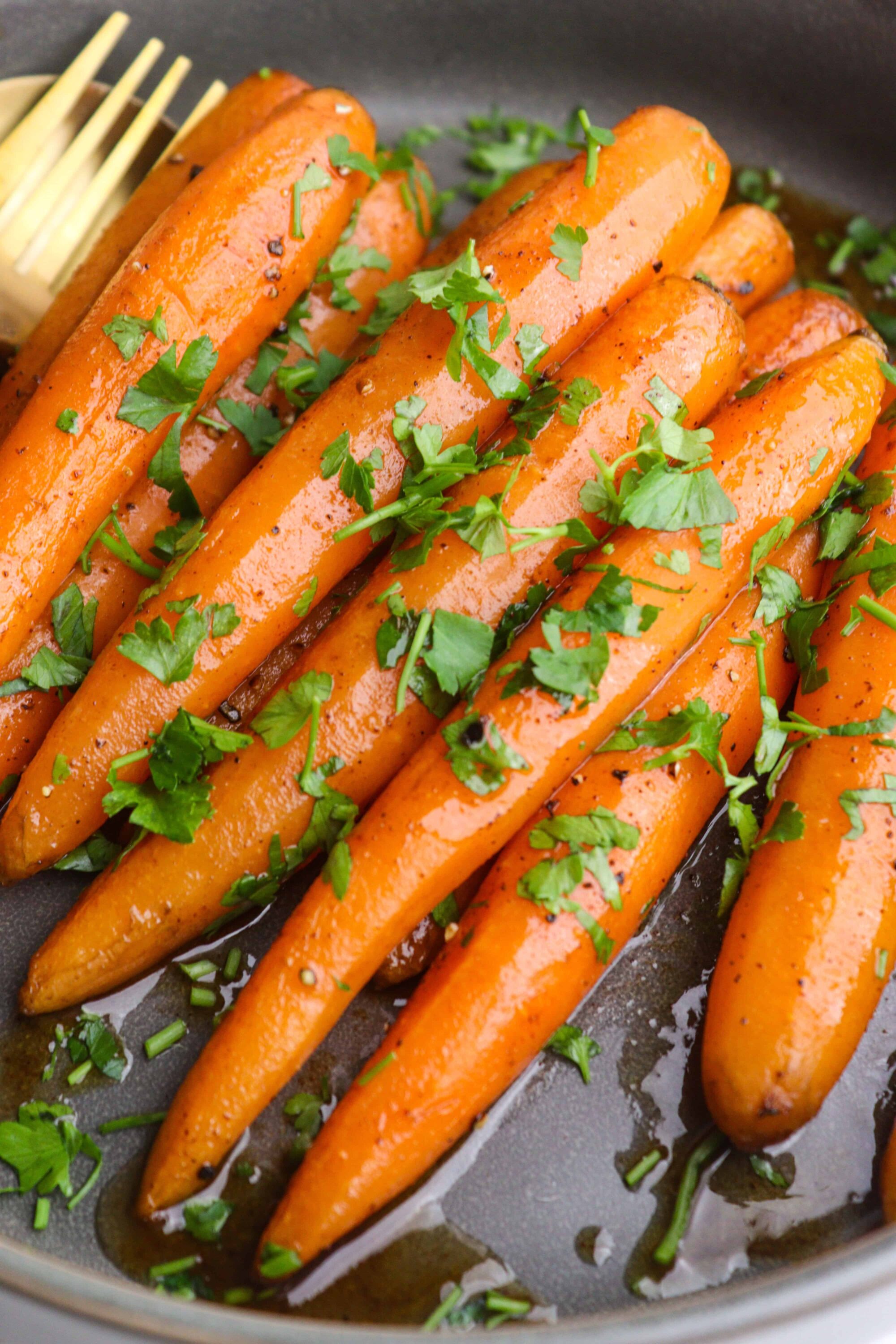 Roasted carrots garnished with chopped fresh parsley in a skillet. Perfect side dish for any dinner.