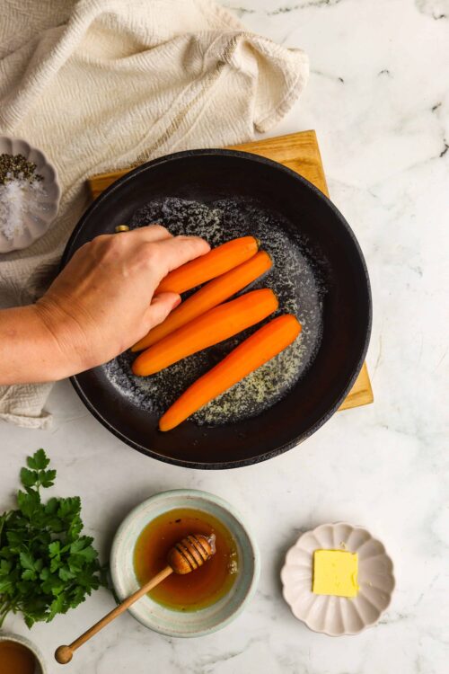 Sweet orange carrots in a black skillet ready for roasting.