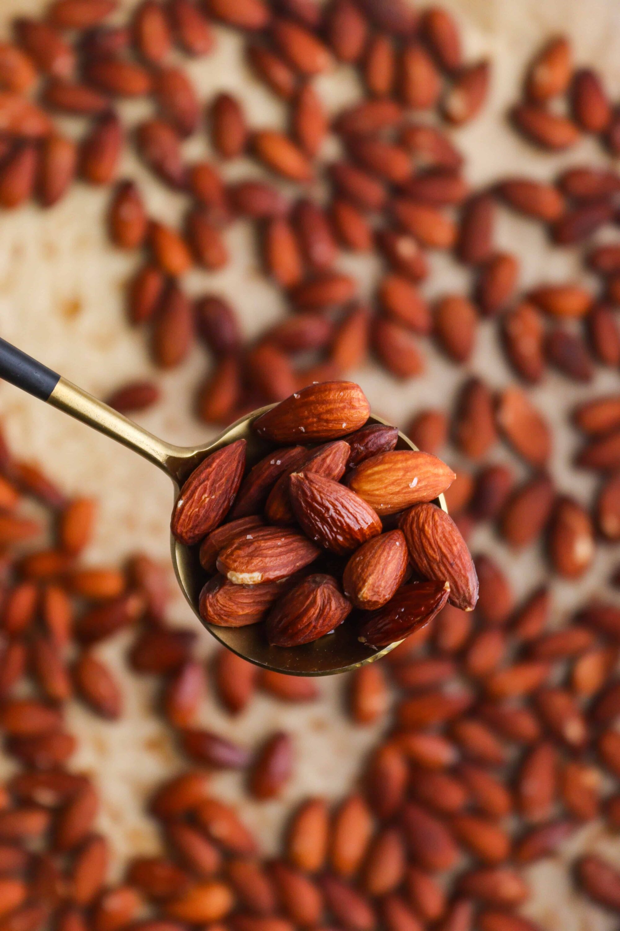 Almond nuts on spoon with scattered almonds background.