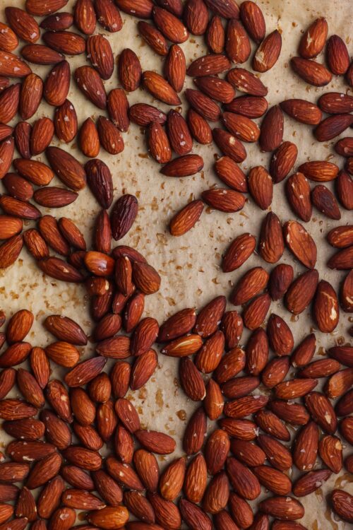 Roasted almonds scattered on parchment paper for baking or snacking.