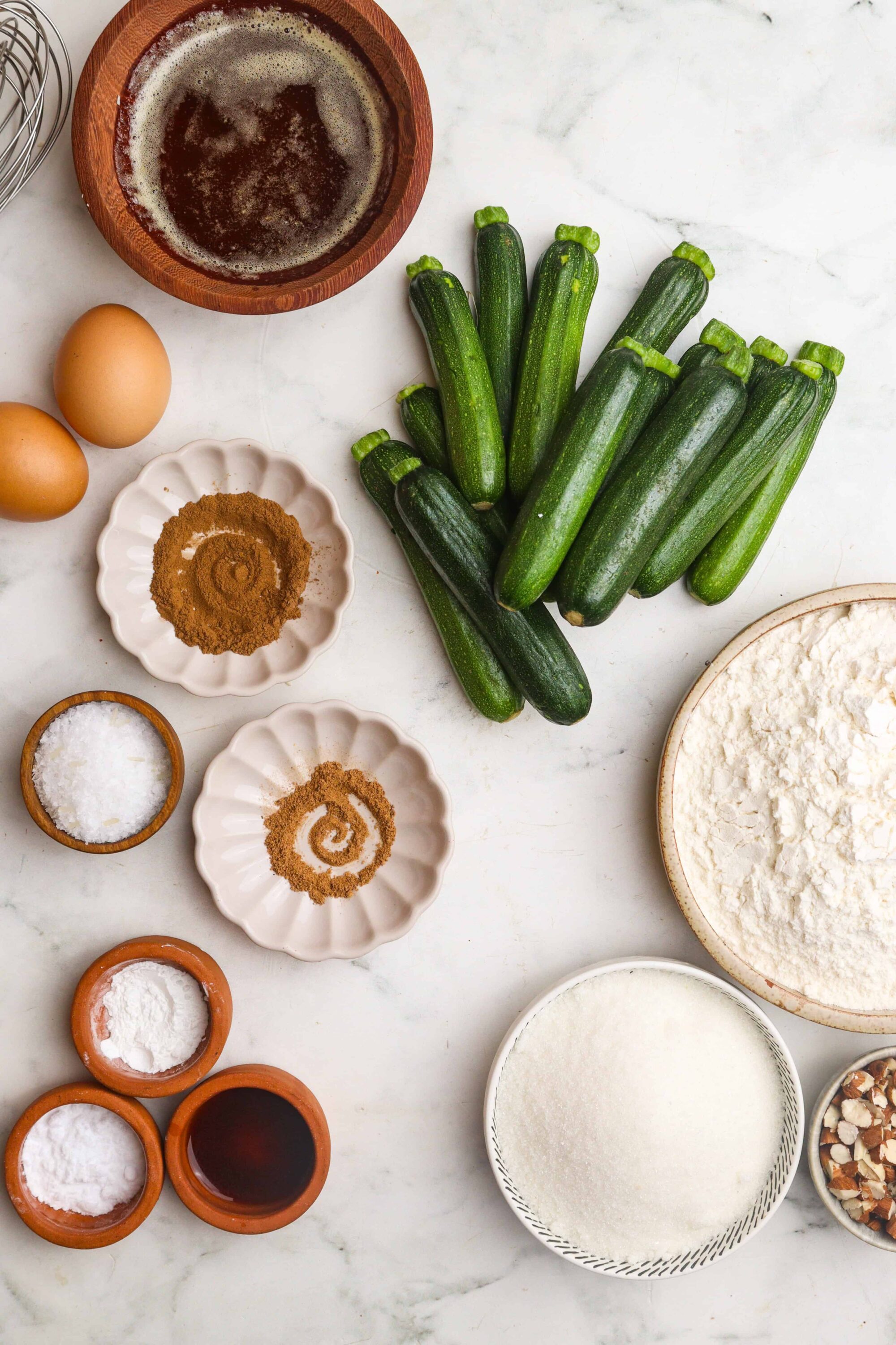 Fresh zucchinis with baking ingredients for zucchini bread or savory baked goods.