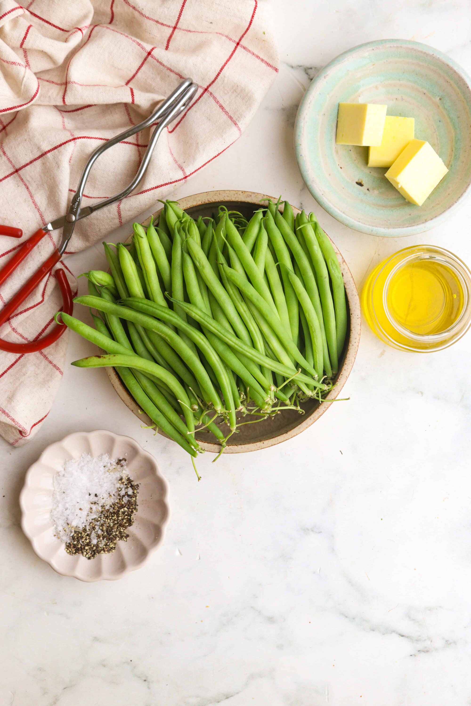 Fresh green beans on a ceramic plate ready for cooking or blanching.