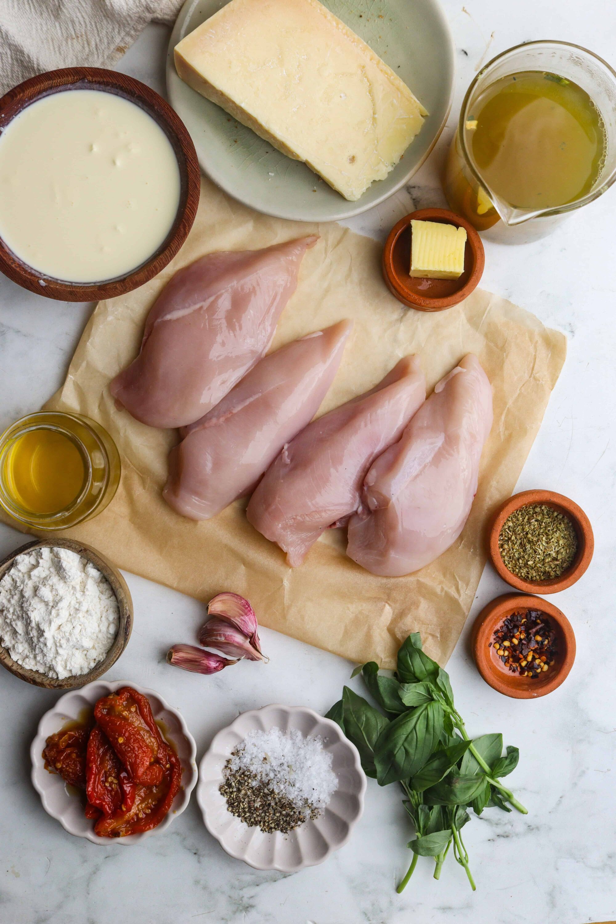 Juicy raw chicken breasts with herbs, spices, cheese, and fresh basil for baking or cooking.