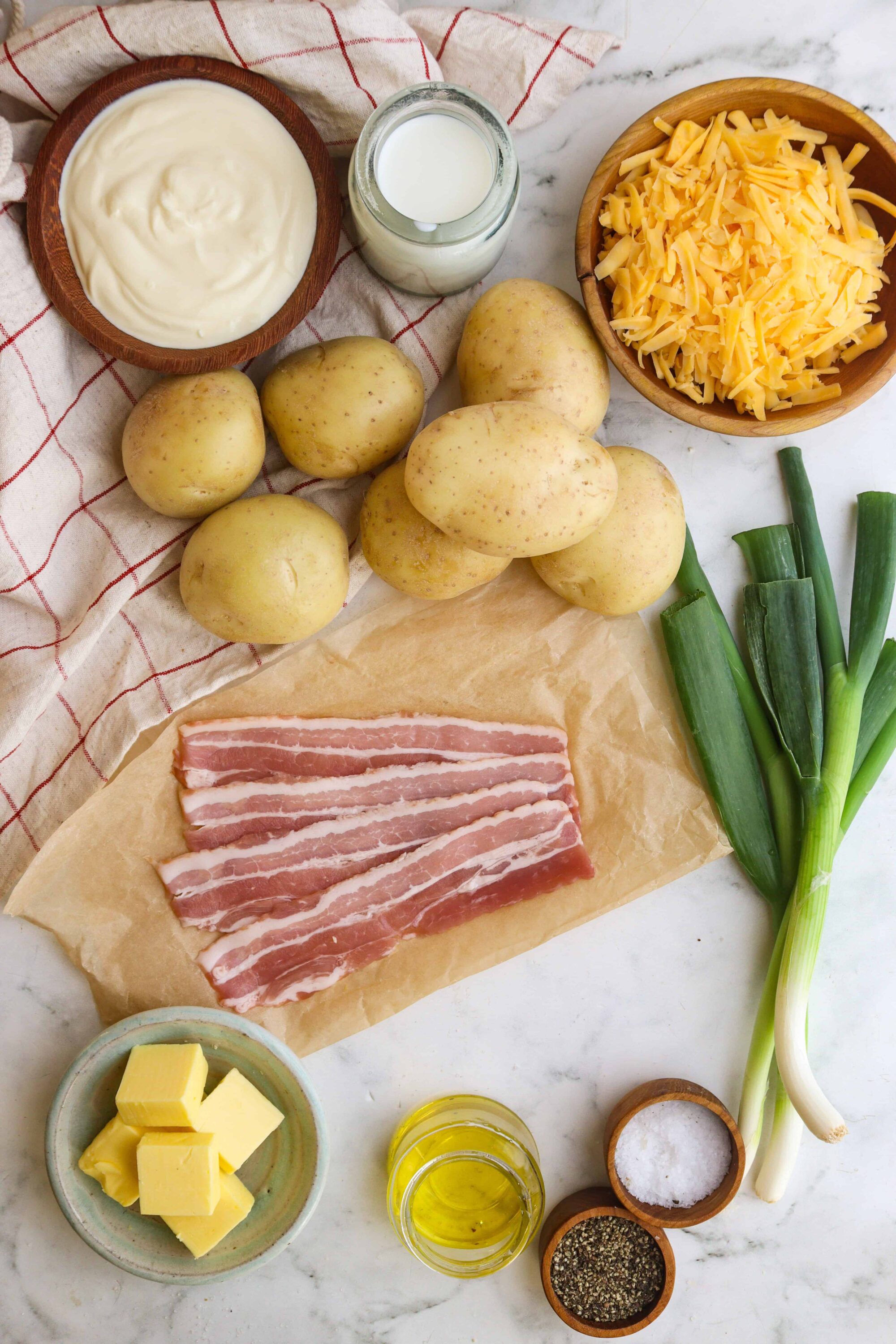 Potatoes, bacon, cheese, sour cream, green onions, milk, and seasonings for baked potato recipe.