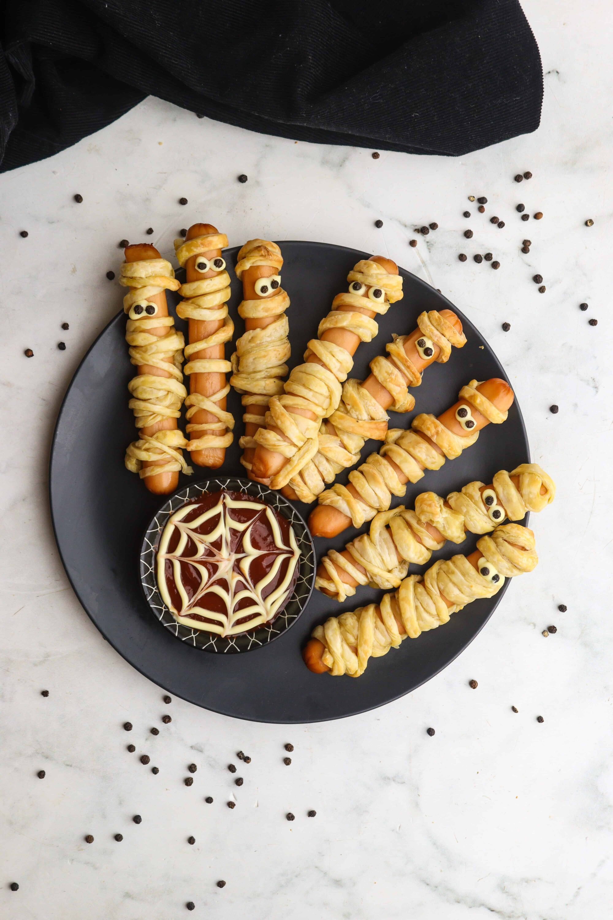 Pretzel hot dogs wrapped in puff pastry with spooky candy eyes for Halloween.